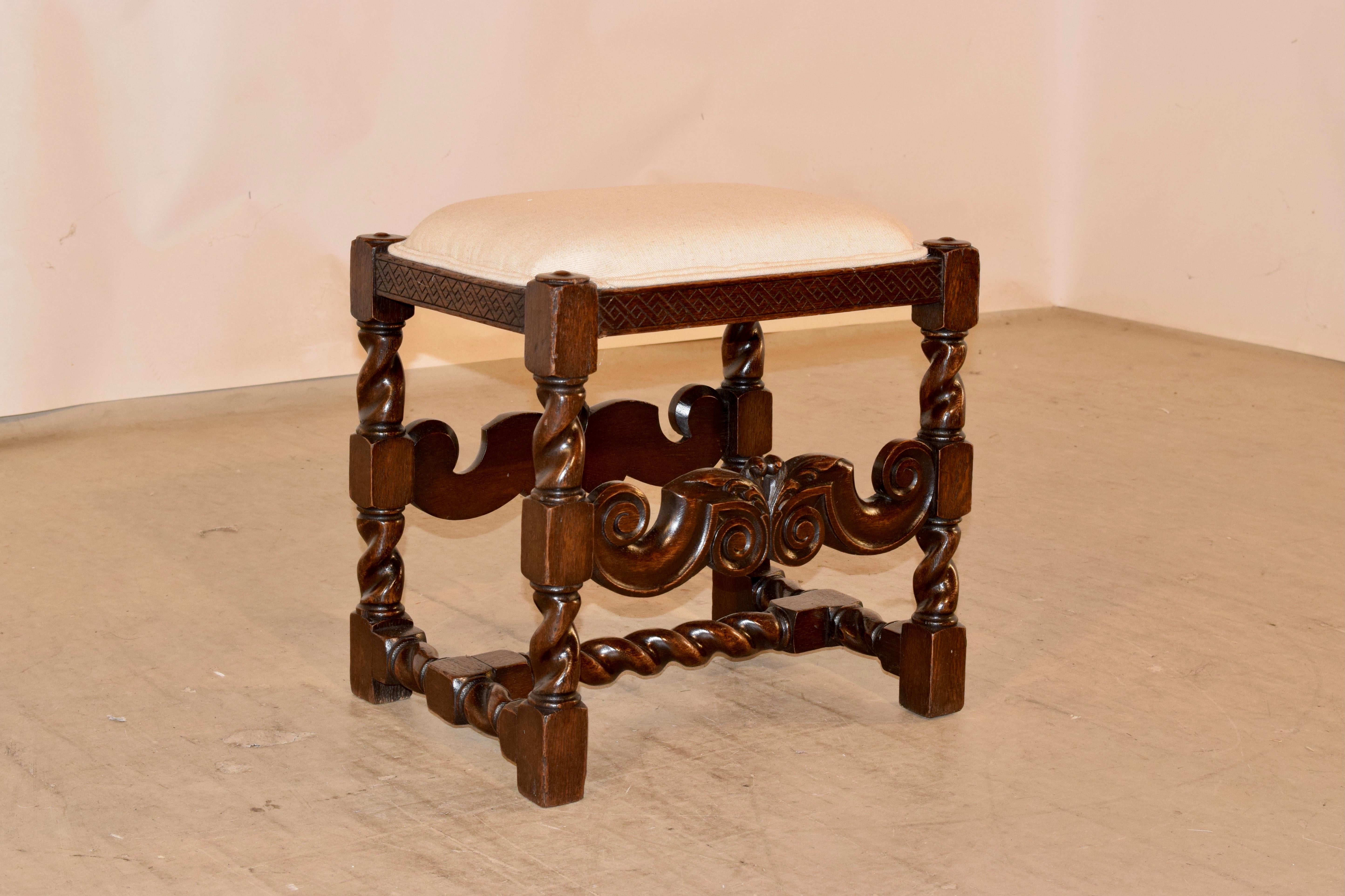 19th century carved oak stool from France with a newly upholstered seat, finished with double welt decoration. The frame has a lovely hand carved decorated rail over hand turned barley twist legs, joined by hand carved stretchers on the front and