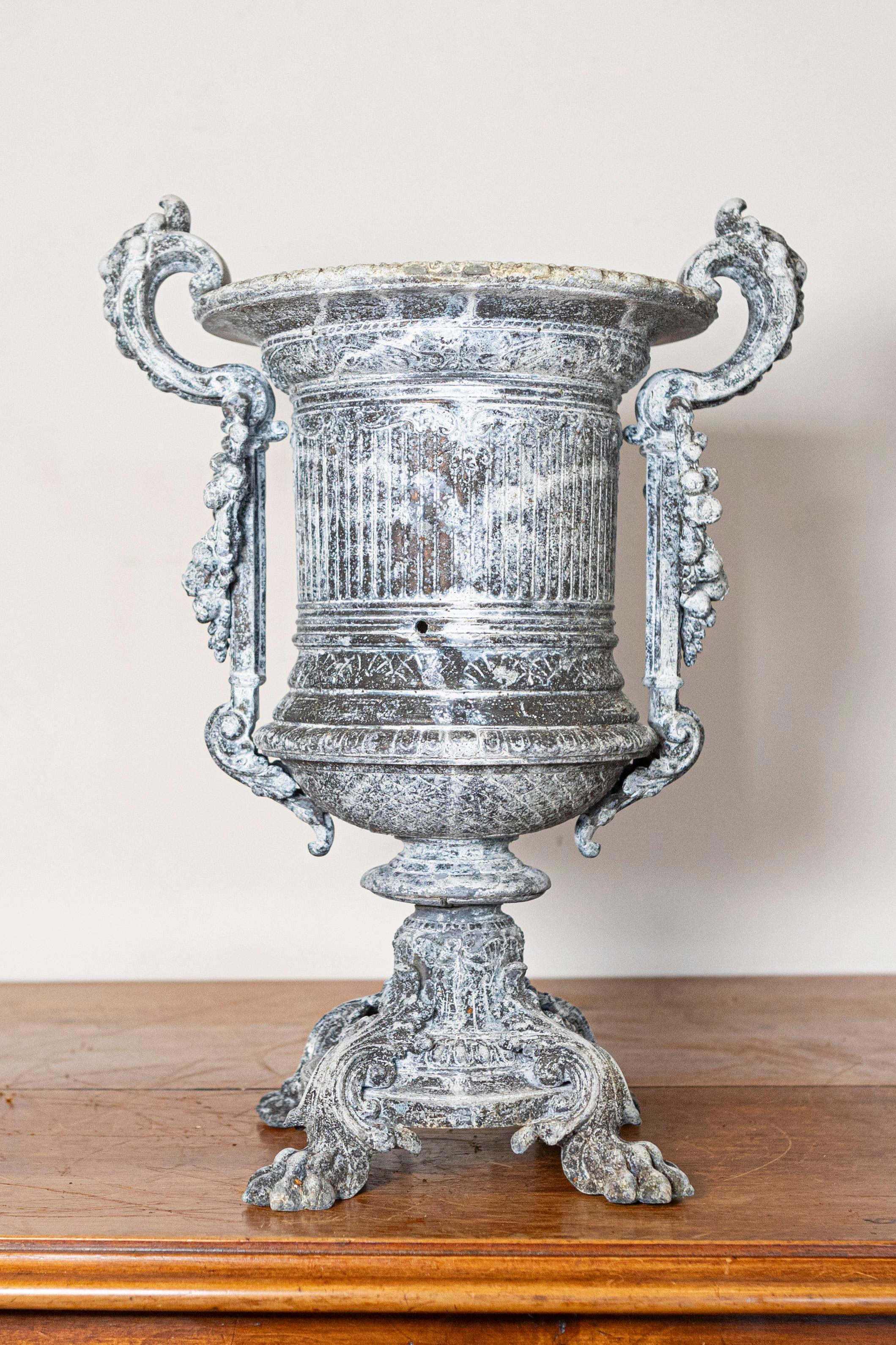 Questa imponente urna francese del XIX secolo è un esempio magistrale di design neoclassico, che incarna eleganza e grandezza. Realizzata in ghisa con una finitura riccamente patinata, l'urna presenta intricati dettagli scanalati sul corpo,