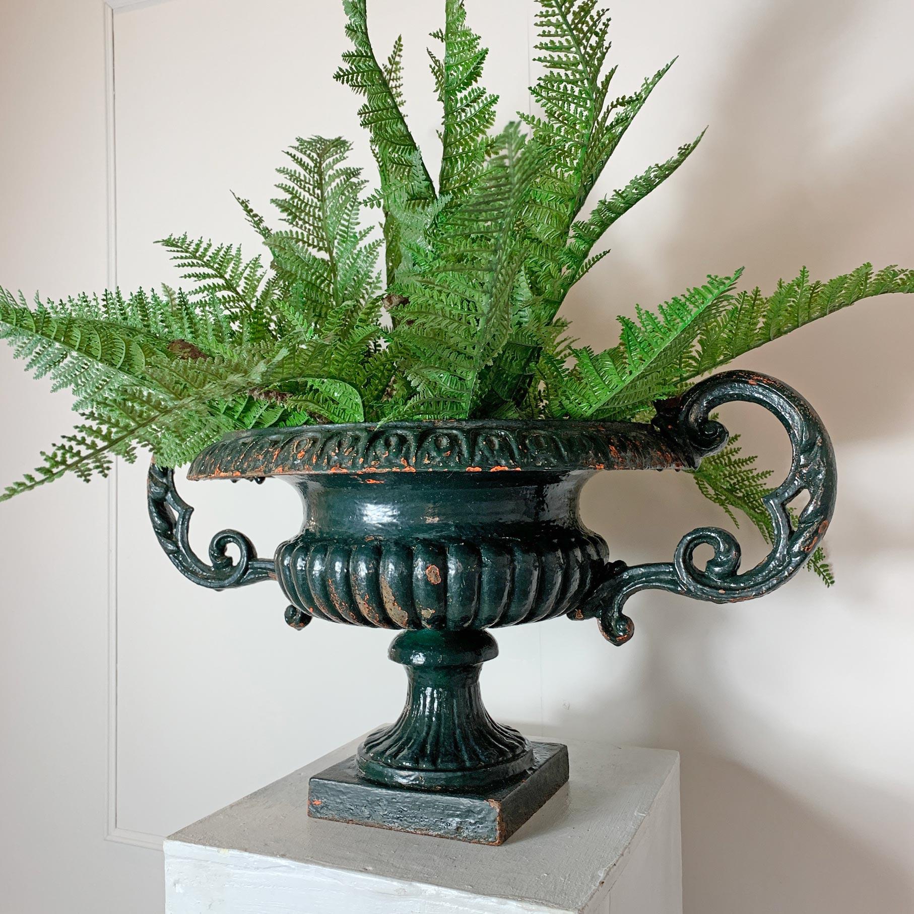 19th century French cast iron urn with decorative twin handles
Bottle green with orangey colored undertones, stunning shape,

58cm width, 39cm depth, 32cm height.
