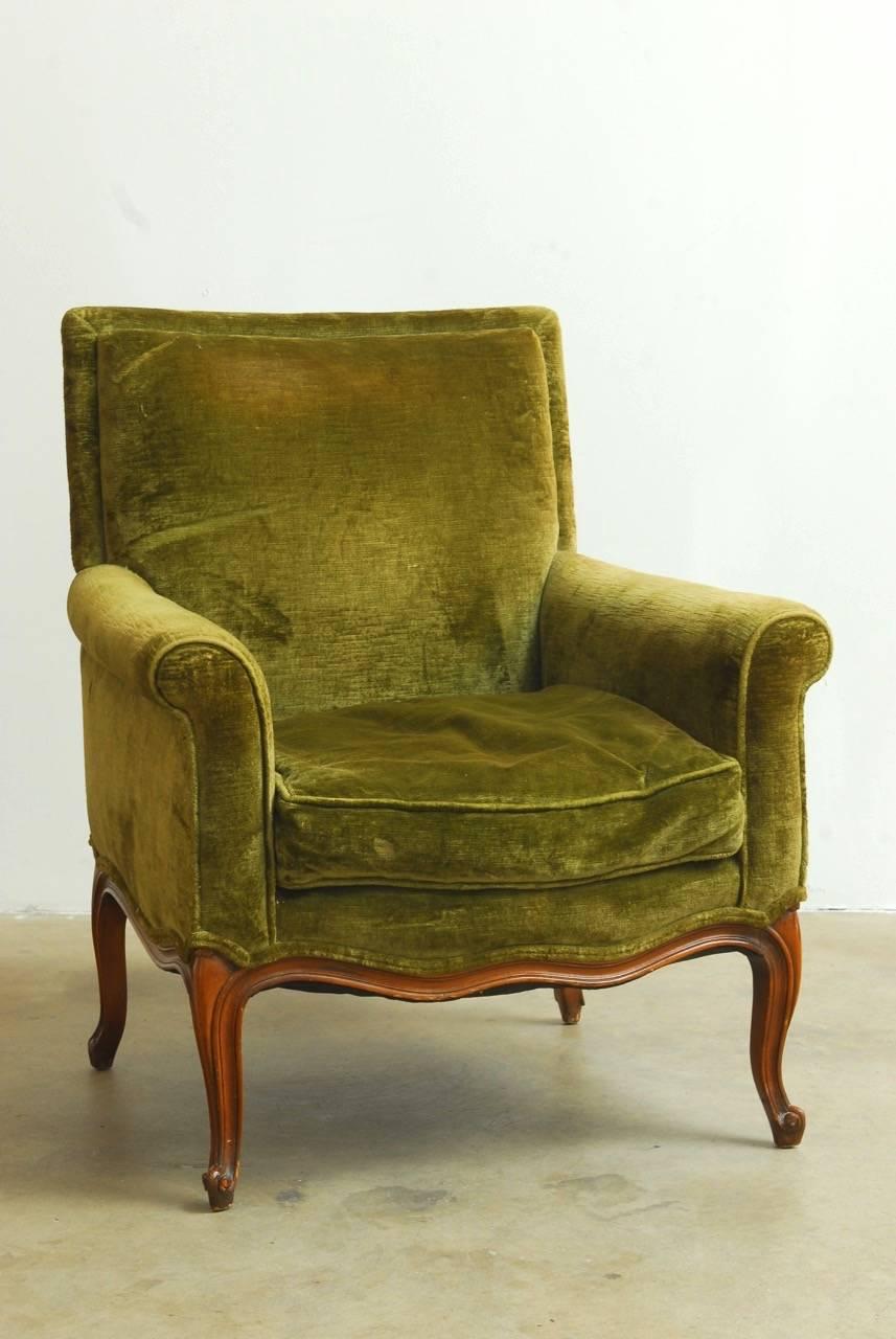 Unique 19th century French green velvet library chair and ottoman made in a transitional style with a Napoleon III design and a Louis XV carved frame. Both the chair and ottoman have beautifully carved serpentine sides and cabriole legs. The ottoman
