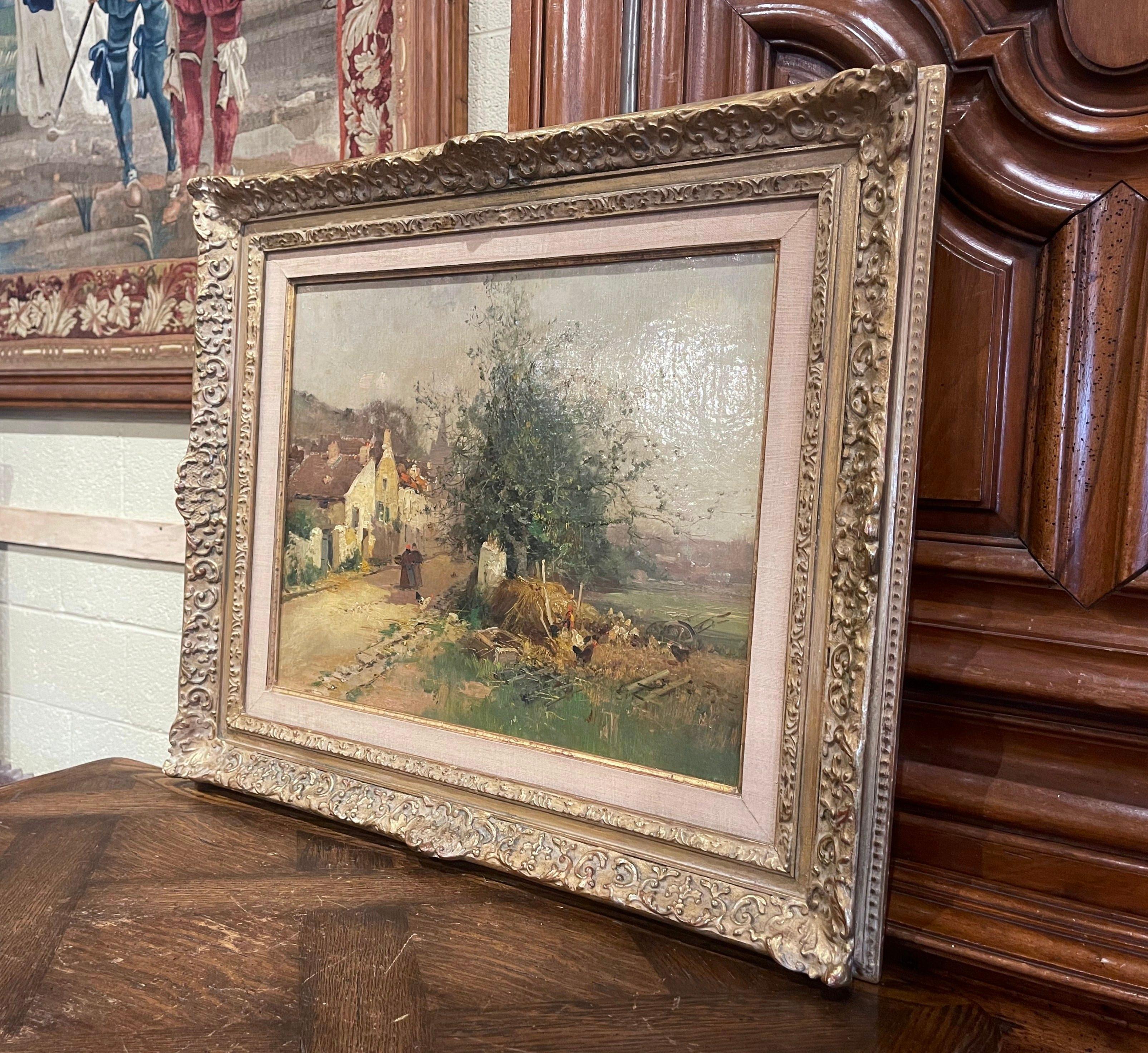 This 19th century impressionist painting was crafted in France, circa 1890. Set in a carved giltwood frame, the artwork painted on canvas, illustrates a picturesque, countryside landscape scene with people, chickens, a village and its road in the