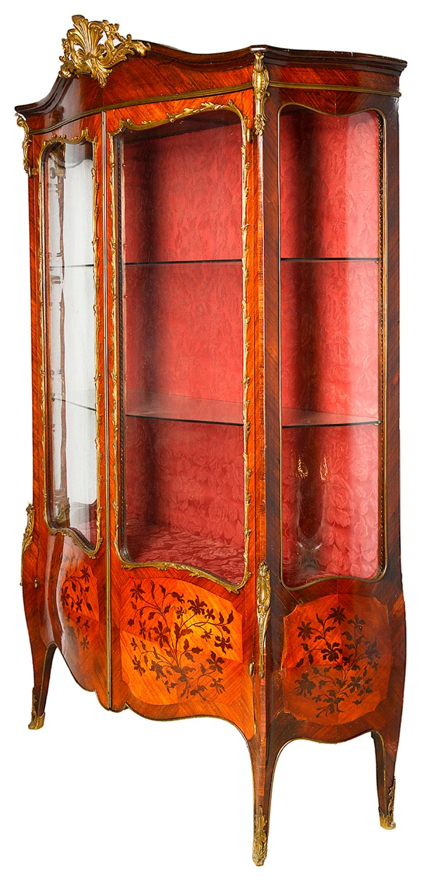 A good quality 19th century French marquetry inlaid vitrine, having gilded ormolu mounts, shaped glass to the sides and doors, glass shelves within and raised on elegant out swept legs, terminating in scrolling ormolu feet.