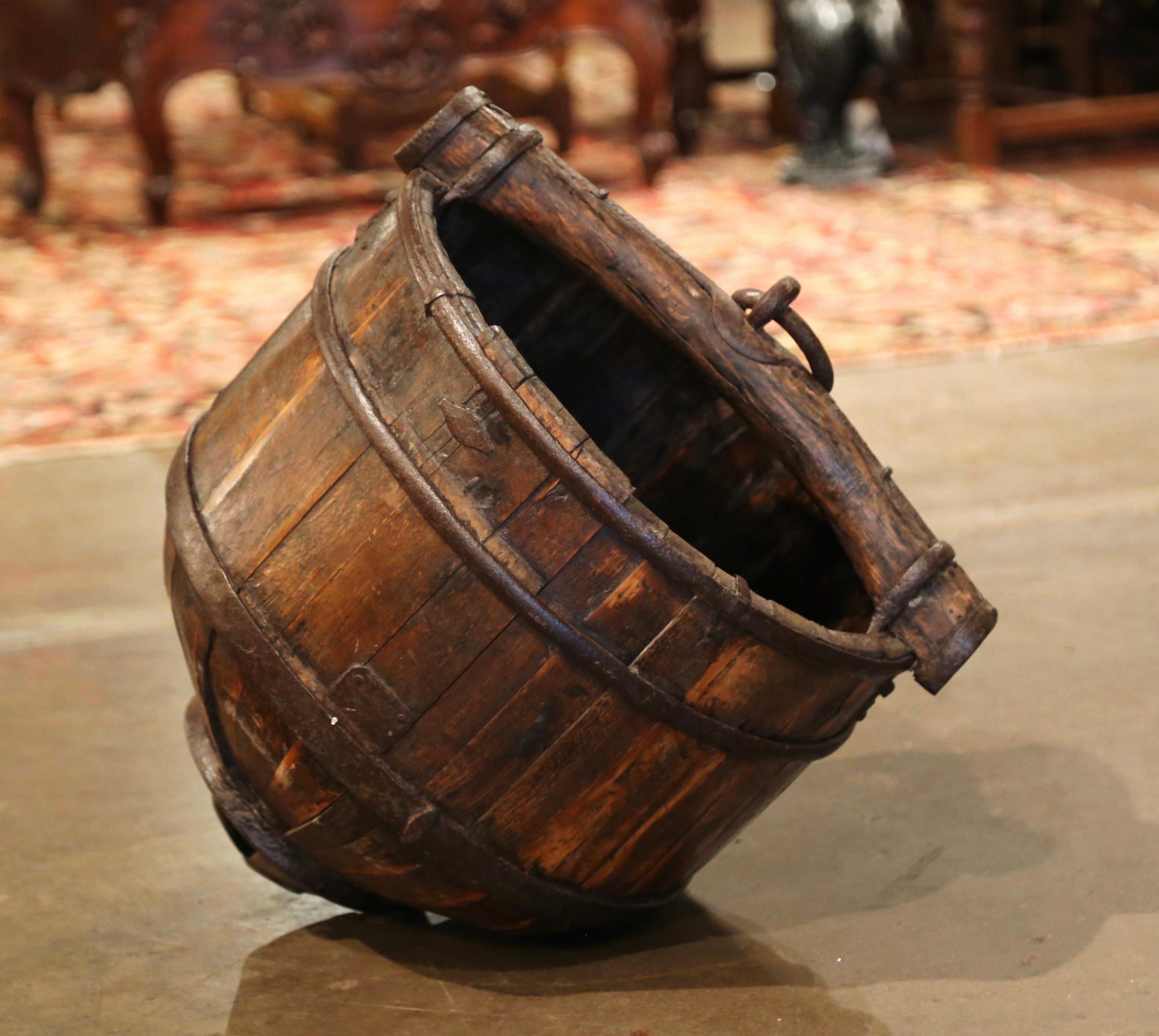 This antique indoor or outdoor planter was crafted in France, circa 1870. With a circular opening and a pointed bottom this top handle bucket, resembling an oxen yoke, features metal bindings and a forged ring attached to the top. This bucket would