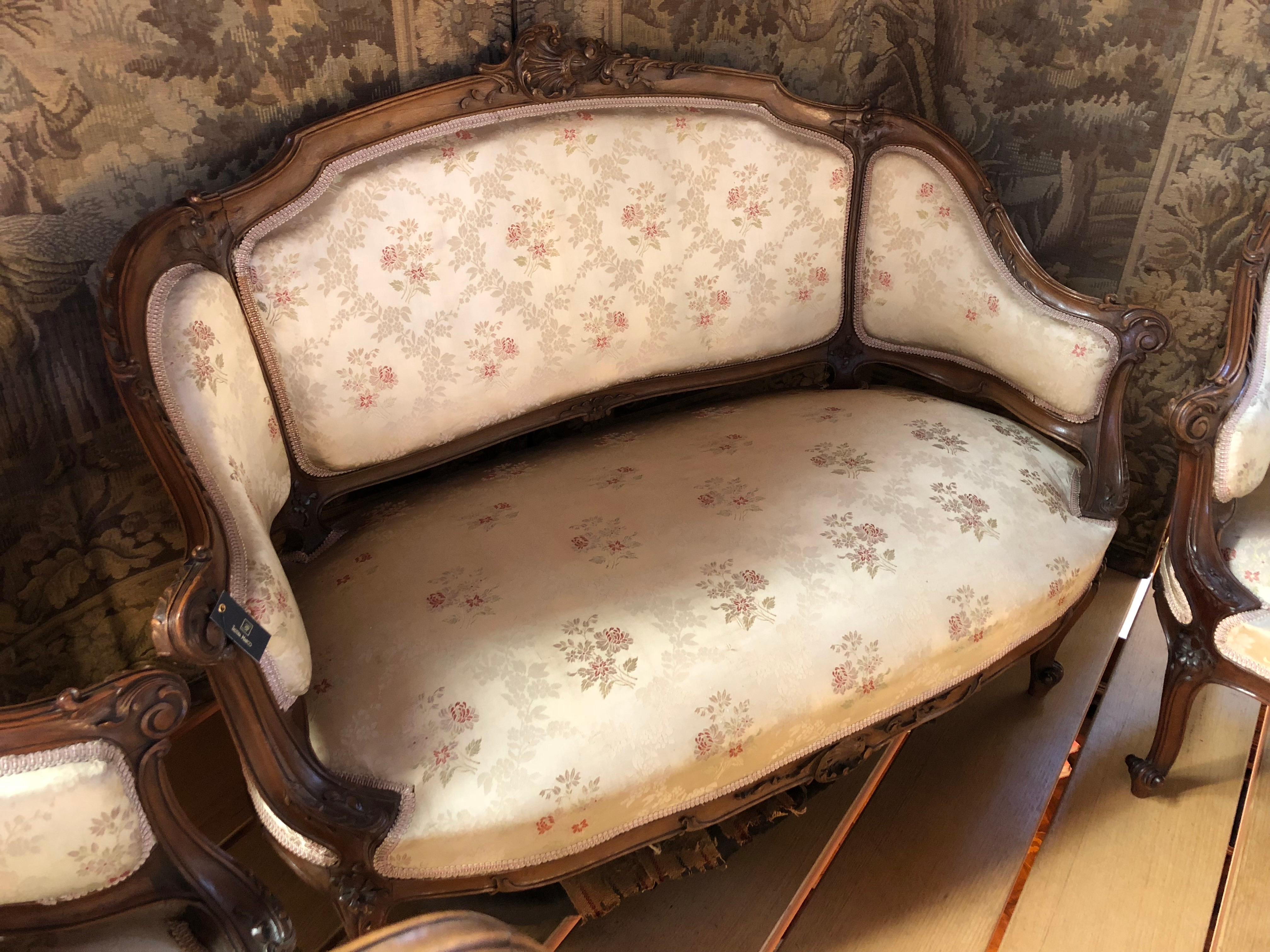 Direct from Paris, this charming five piece French salon set features, one settee, two arm chairs and two petit side chairs. Original fleur silk upholstery creates an utter feminine touch to the set, and walnut frames add to the chairs' luxurious