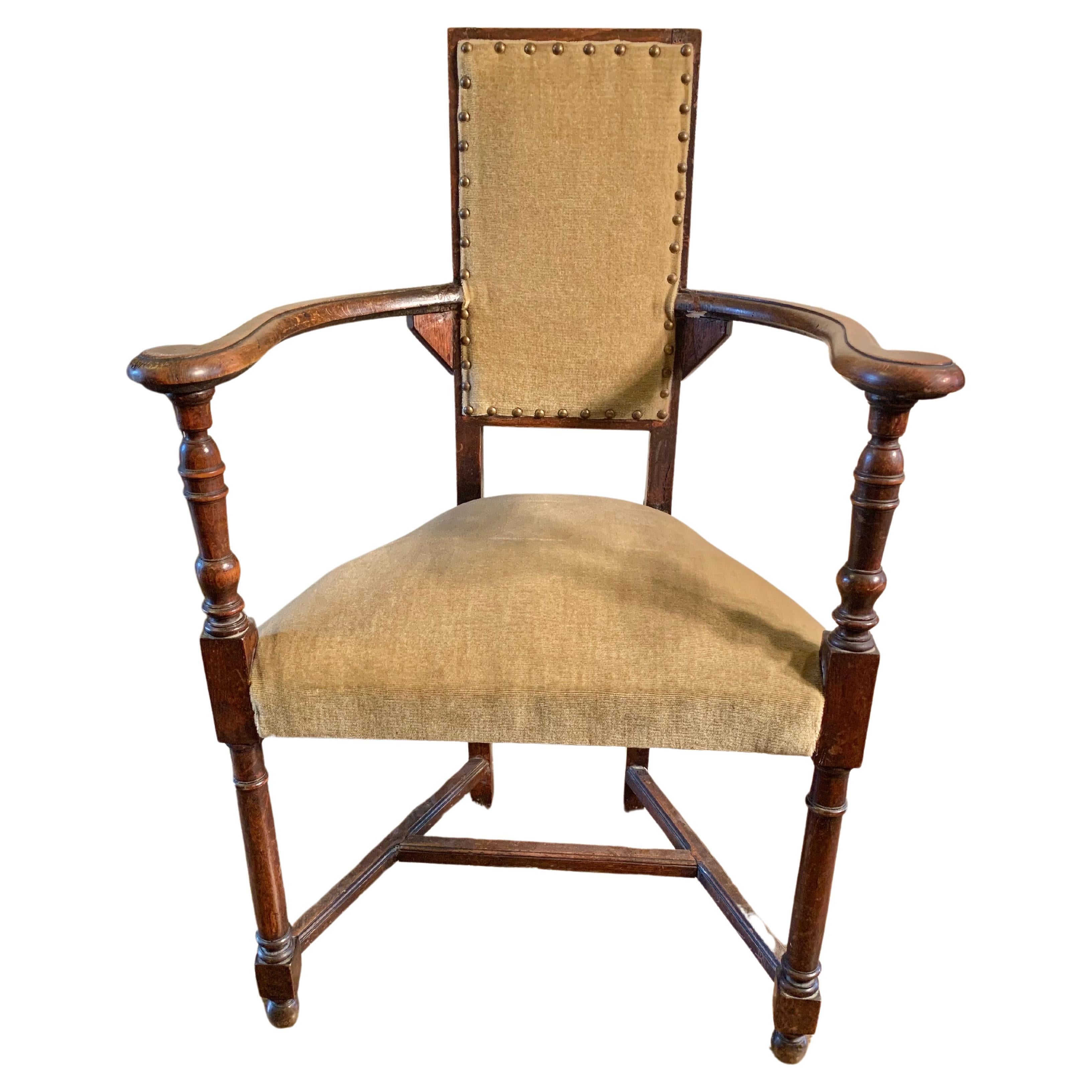 Found in the South of France, this 19th Century French Armchair was crafted from walnut in the mid 1800's. Presented as found in it's original upholstery, the piece features hand carved wide set armrest that end in a slight scroll. The arms rest on