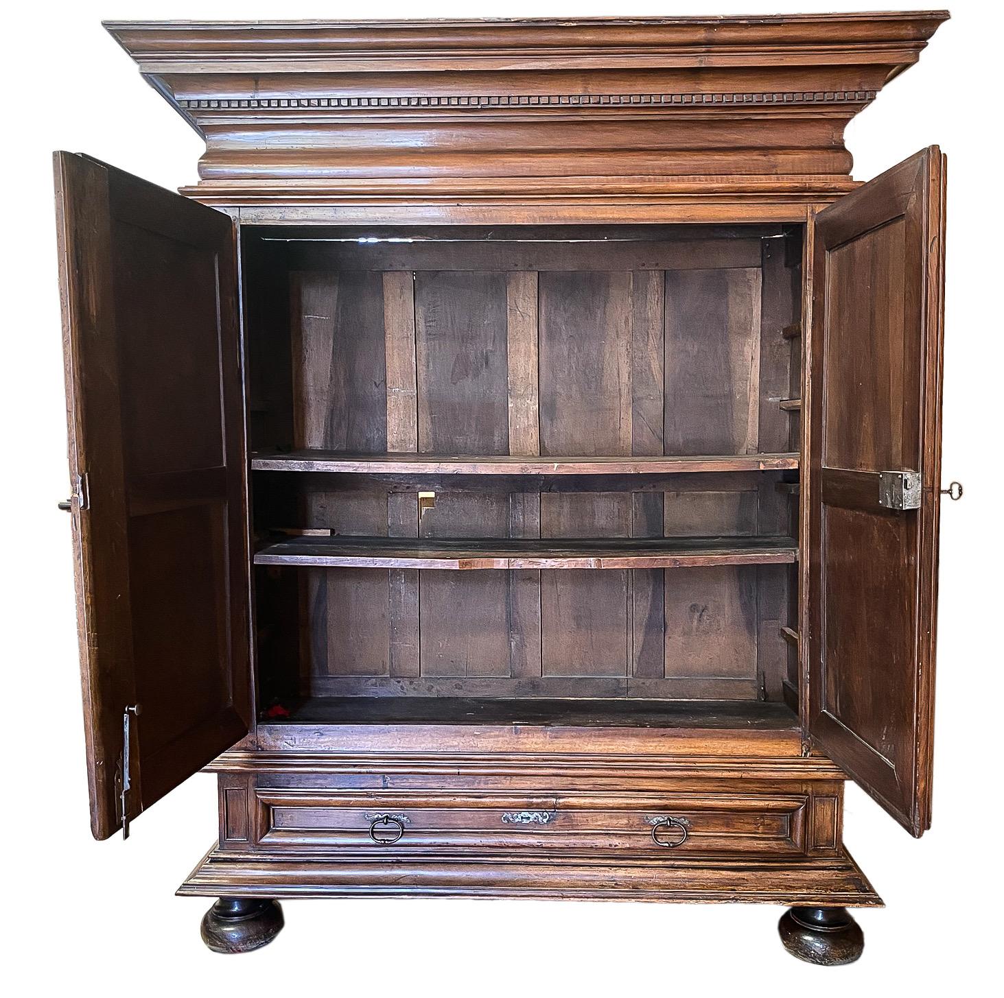 Crafted in Southern France, circa 1820, the large cabinet is built in three sections, the upper section features a wide crown at the top. Two heavy doors decorated with high relief carved diamond shape geometric designs revealing two inside shelves