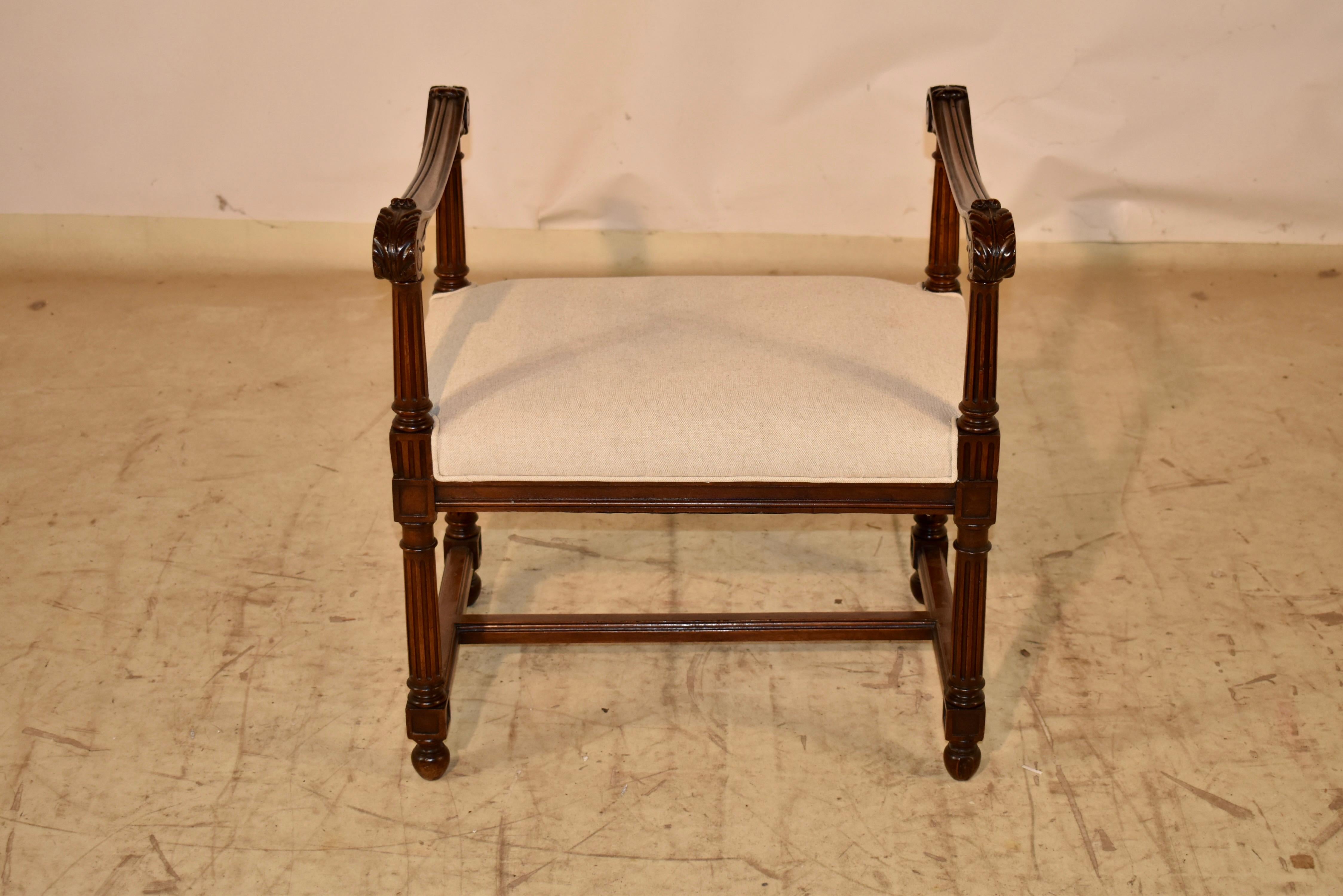 Panca francese del XIX secolo con braccioli.  La struttura è realizzata in noce e presenta due bracci intagliati a mano e sagomati a volute, che poggiano su supporti scanalati.  La seduta è stata rivestita di recente in lino e rifinita con una