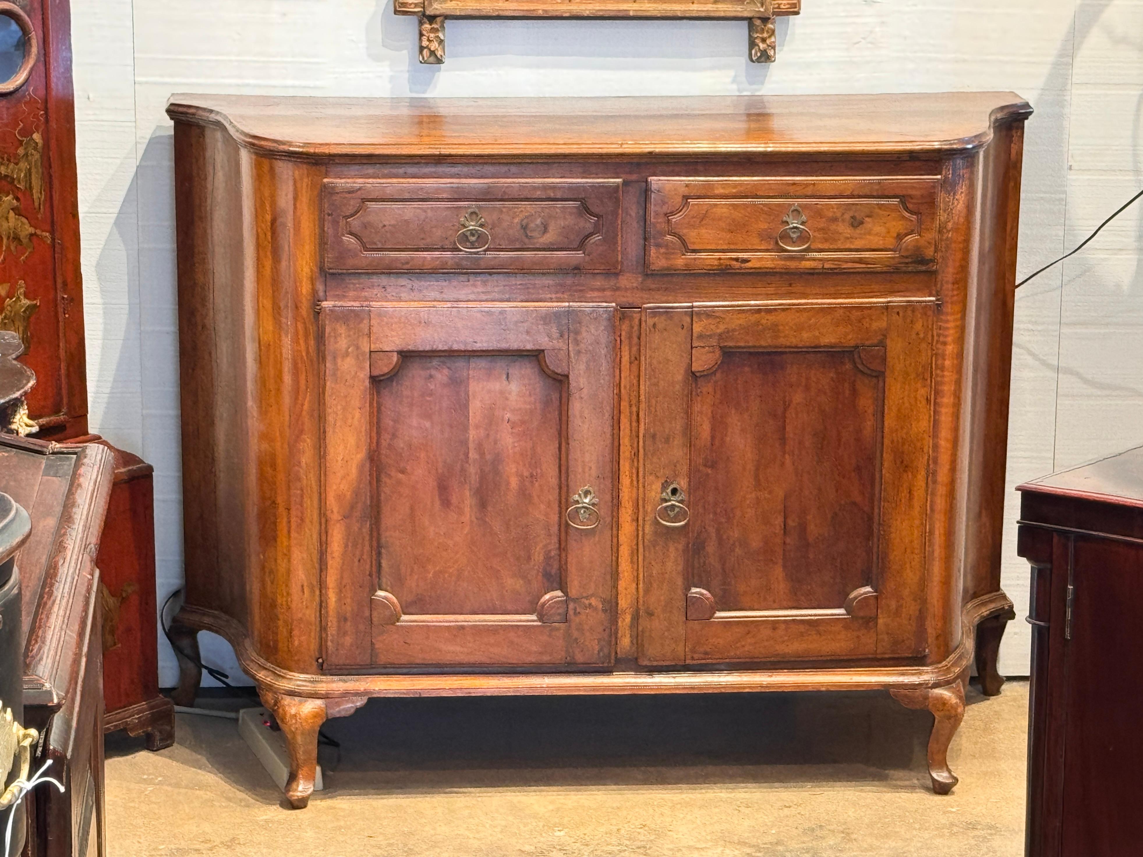 Buffet français en noyer du 19e siècle avec des coins façonnés, des portes à panneaux et des façades de tiroirs sculptées. Reposant sur de courts pieds cabriole et dotée de poignées en laiton, cette armoire présente un intérieur épuré avec un dos