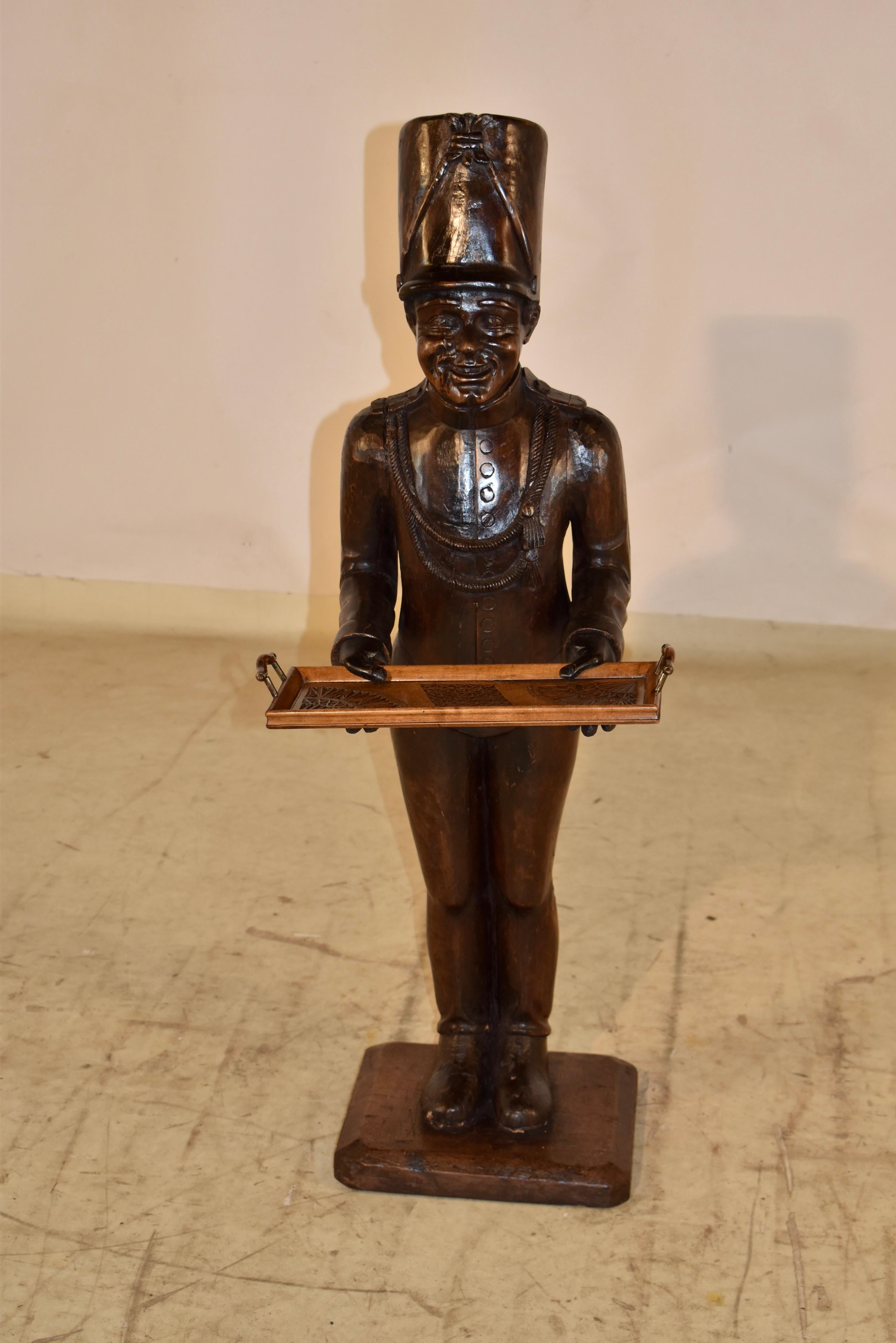 Statue d'art populaire unique du 19e siècle représentant un soldat français tenant un plateau.  La statue est sculptée à la main dans du noyer et c'est un petit bonhomme si sympathique !  Son sourire illumine la pièce, tandis qu'il vous invite à