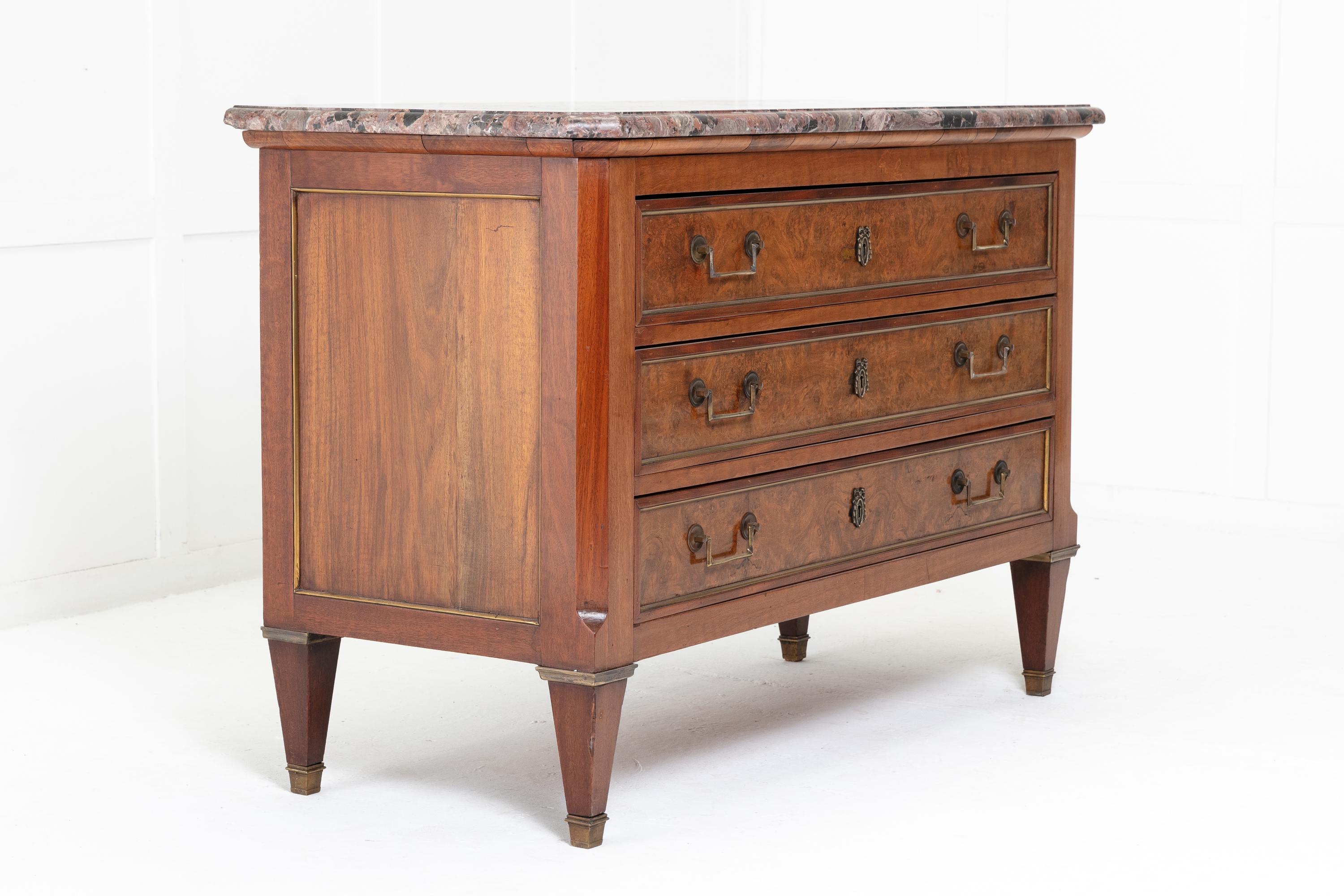 19th century French walnut commode with a stunning marble top having three brass moulded drawers with burr walnut panels flanked by canted corners. Raised on square tapering feet with brass sabots.
 