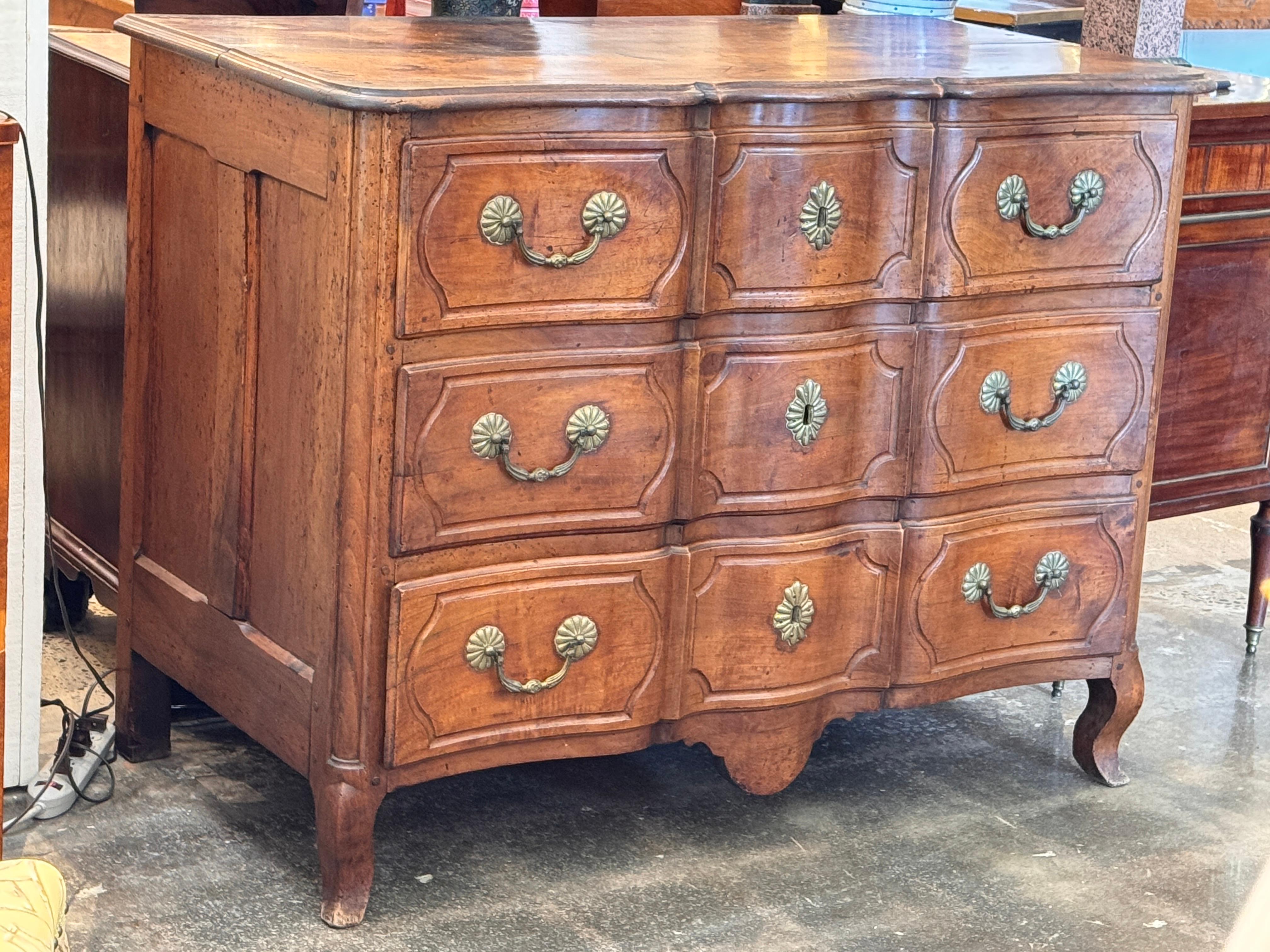 Elegante commode française du 19ème siècle en cerisier avec une façade en forme de serpentin et des panneaux latéraux. Le coffret à trois tiroirs présente des façades de tiroirs en forme avec des bords moulés et des ferrures à rosettes en laiton
