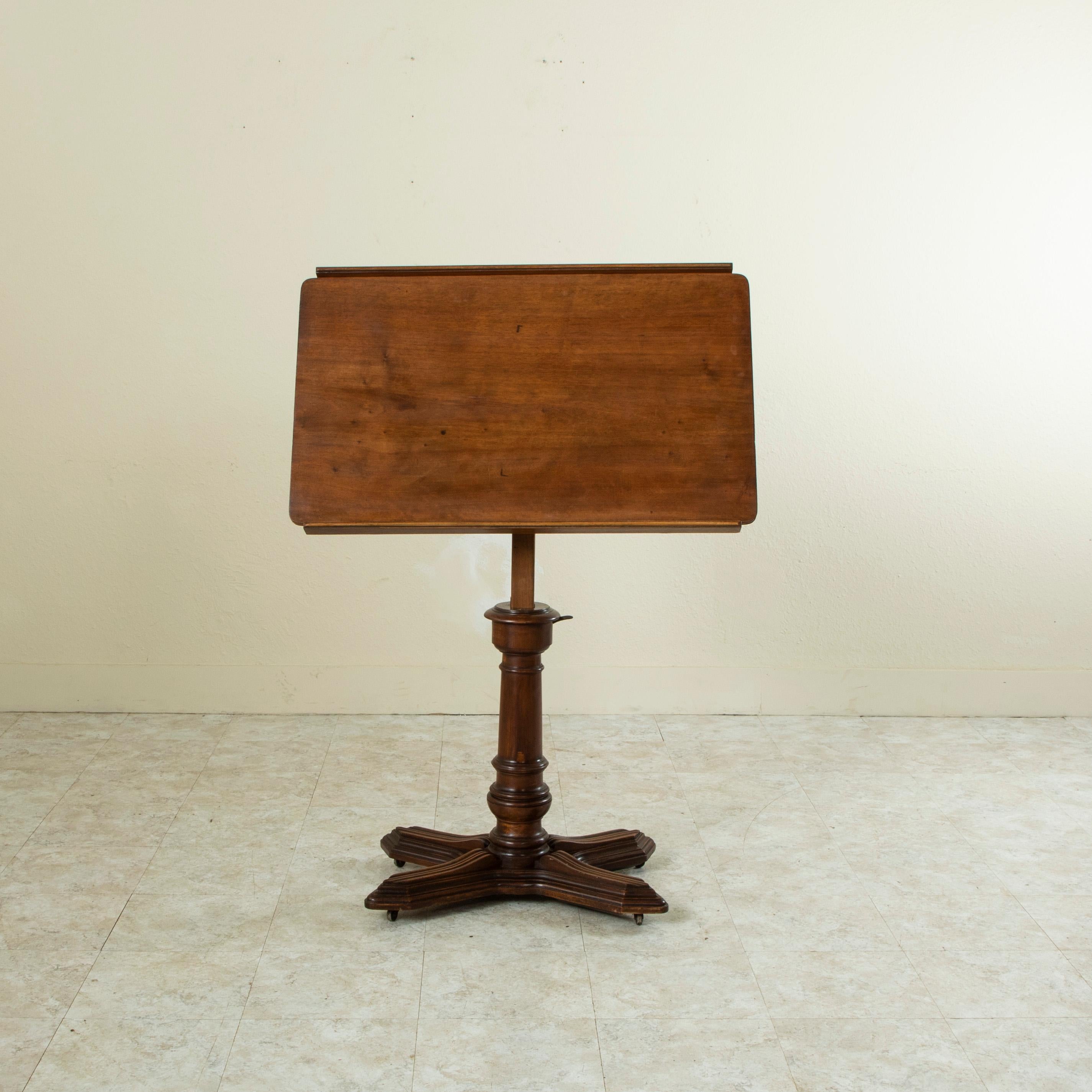 This late nineteenth century French walnut adjustable architect’s drafting table features the maker's label, E. Chouanard. The table top adjusts in pitch, height, as well as right and left orientation, and is supported by a turned central column on
