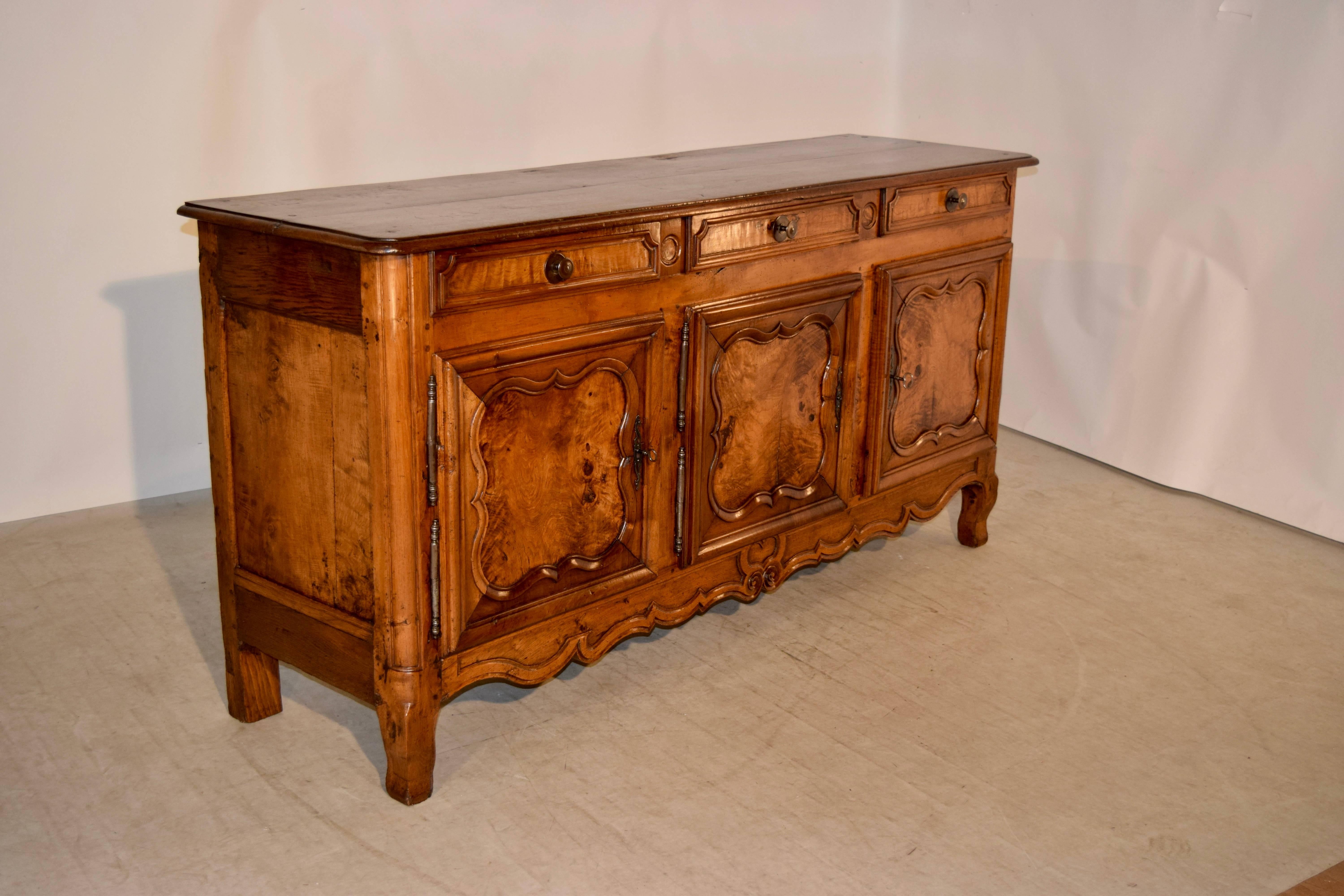 19th century enfilade from France made from walnut. The top has a beveled edge and is beveled around the edge, following down to three drawers with hand paneled drawer fronts over three hand paneled doors with raised paneled fronts and central