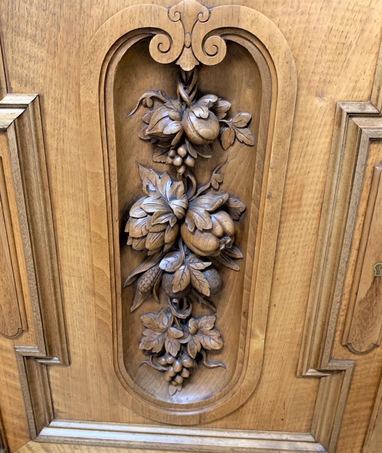 Outstanding 19th century French walnut bookcase cabinet featuring highly detailed carvings of lion heads, fruits, grape leaves, flowers, and a variety of vegetables. The frosted and etched glass double doors rests atop two drawers and two cupboards