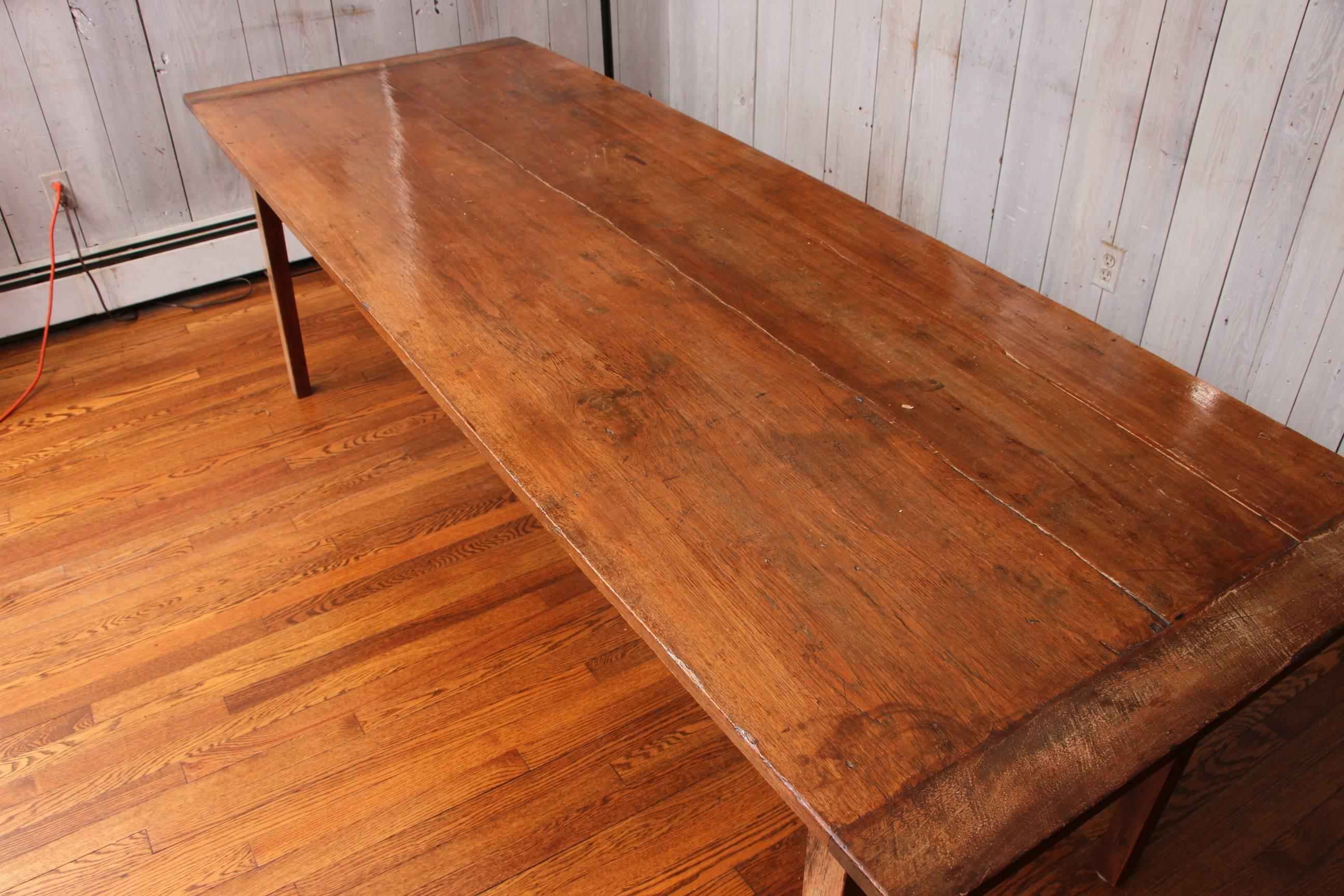 19th century farm dining table, walnut, overhanging rectangular plank top over pull out extension table, supported on square tapering legs, appears refinished.

Condition: Expected wear and signs of use consistent with age.