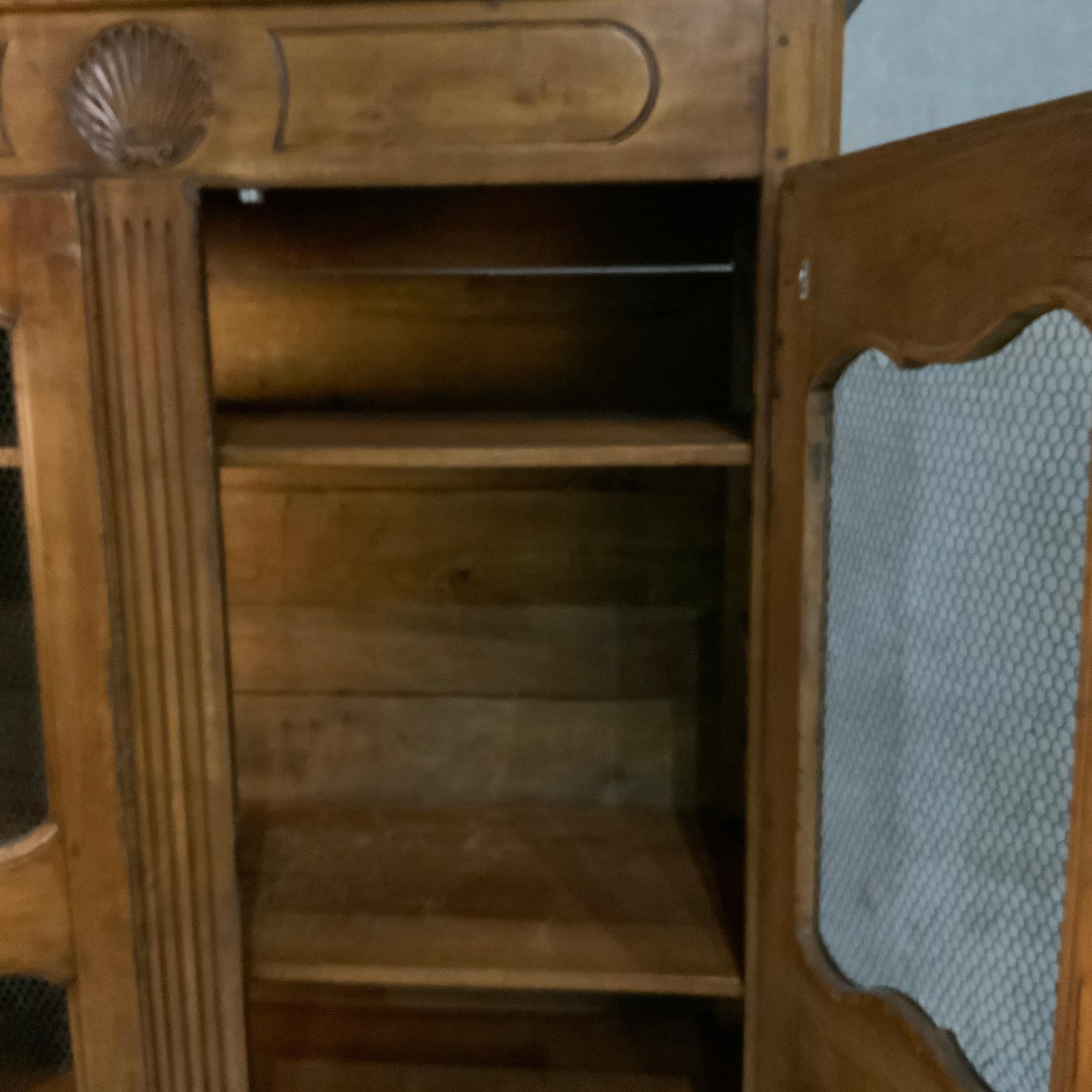 Zweitüriger Schrank mit dekorativ geschnitztem Muschelmotiv. Die Türen sind mit Hühnerdraht versehen und lassen sich öffnen, um einen Innenraum mit Regalen freizugeben. Erworben aus einer Privatsammlung. Dies ist ein vollständiges Stück ohne