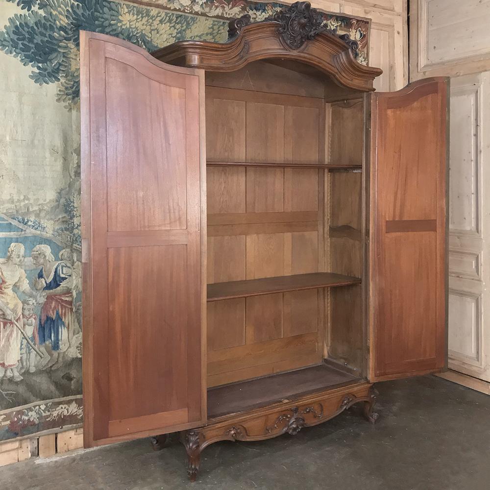 19th century French walnut Louis XV armoire is of a transitional nature, with symmetry appearing in the design as a departure from the Rococo naturalistic look. The stately appearance of this gem exudes from the exquisitely carved arched crown