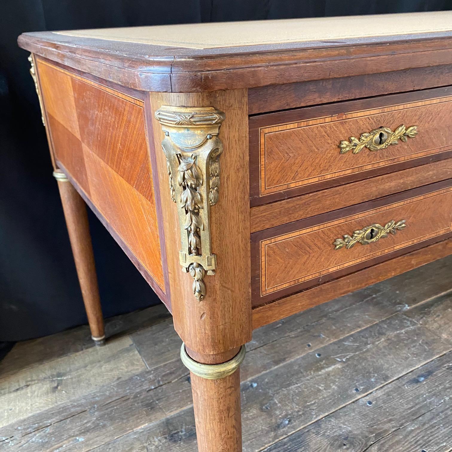 Beautiful 19th Century French Walnut Louis XVI Desk with immaculate new embossed leather writing surface. French Louis XVI bureau plat table desk with five spacious drawers and lovely classic inlaid woods with bronze trim and swags on the tops of