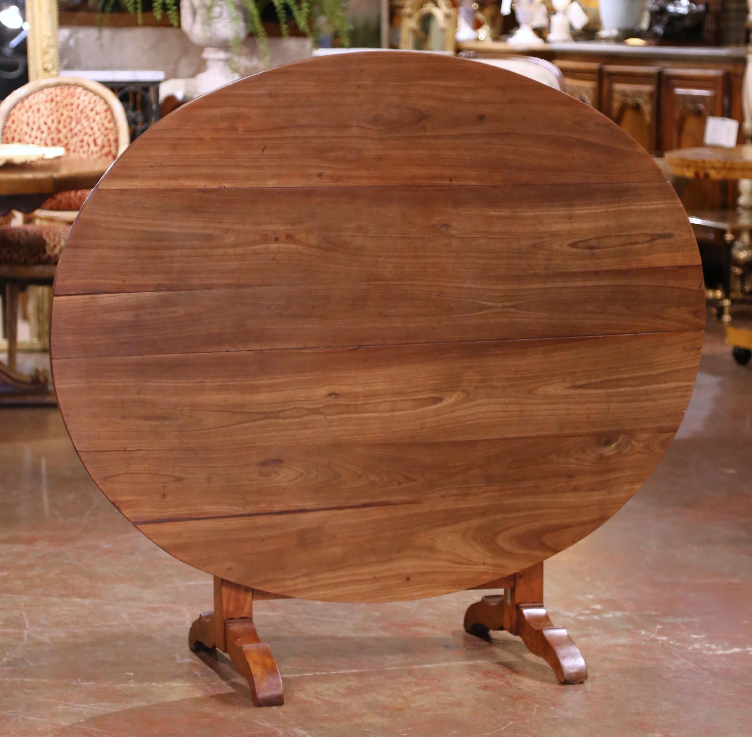 This antique oval tilt-top wine tasting table was crafted in France circa 1870 from solid walnut, representing both practicality and elegance in provincial furniture design. The oval plank top, measuring 51.5 inches wide by 42 inches deep, displays