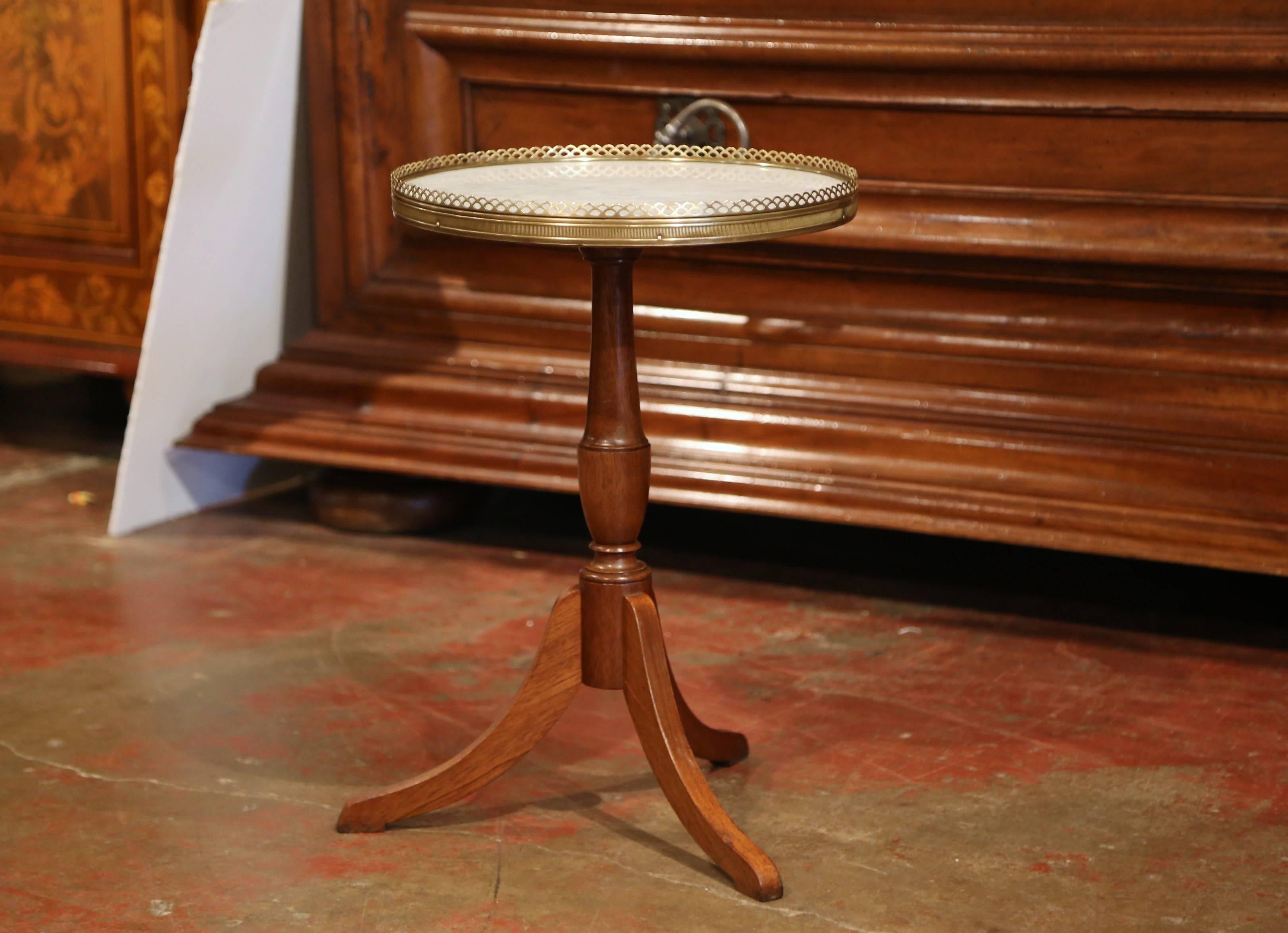 This elegant side table was crafted in France, circa 1890; sited on a carved pedestal with three legs, the small fruit wood table features a brass gallery rim with white marble inset. Excellent condition with rich walnut patina.
Measures: 14