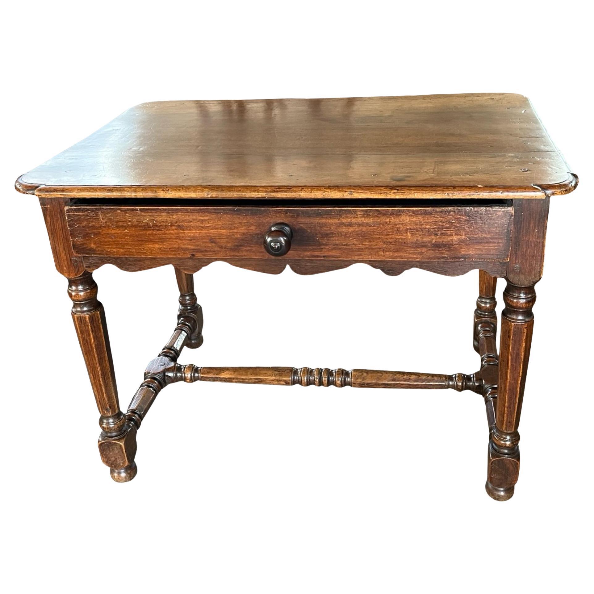 Side table hand-made in France in the mid 1800s using walnut and pegged construction. The table features a single, inset drawer on the front of the apron and scalloped edges on all sides. The top is made of three boards with ogee edges and rounded