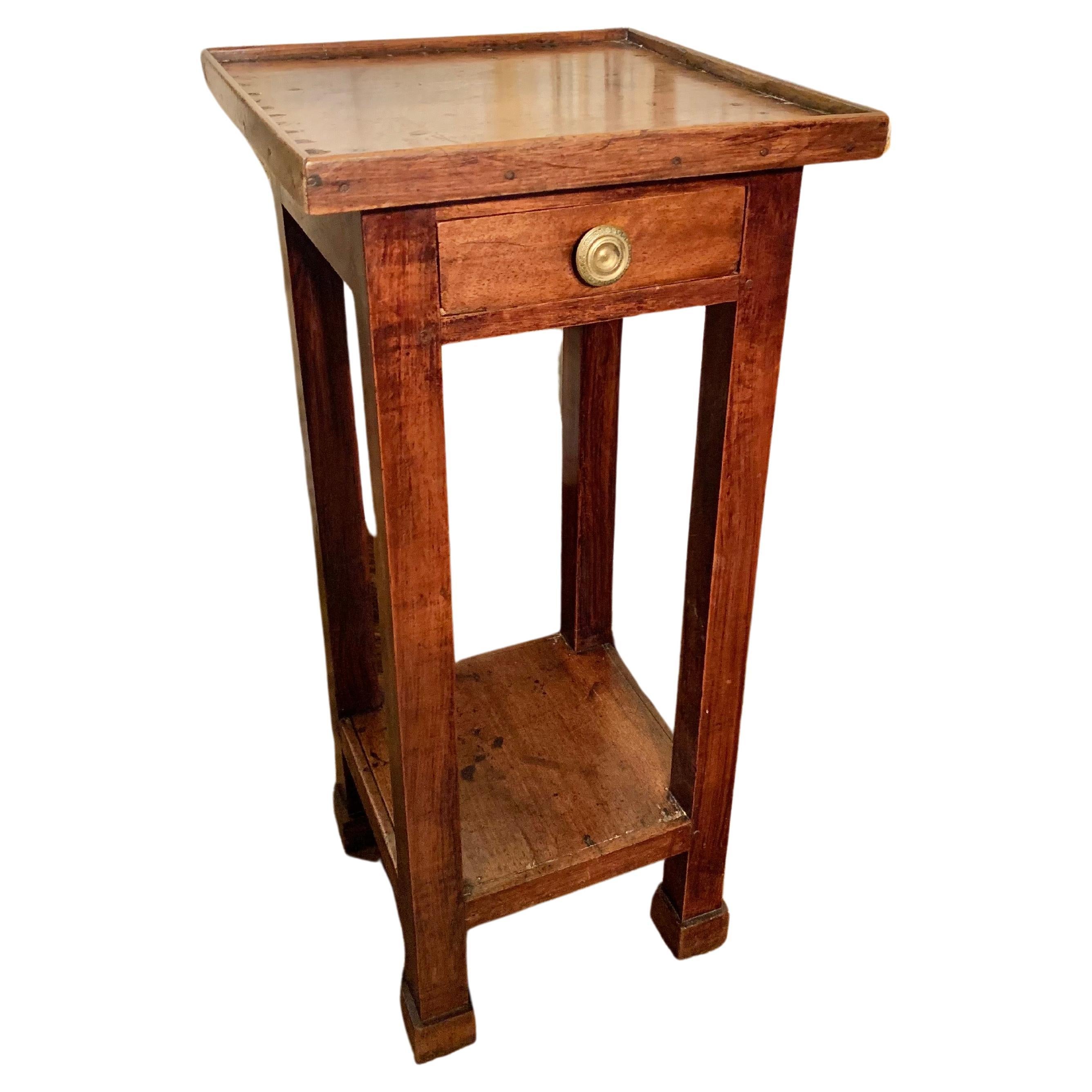 Trouvée dans le sud de la France, cette table d'appoint du XIXe siècle a été fabriquée en noyer par des artisans français dans les années 1800. La pièce présente un plateau en bois reposant sur un tiroir et se termine par quatre pieds carrés. Le