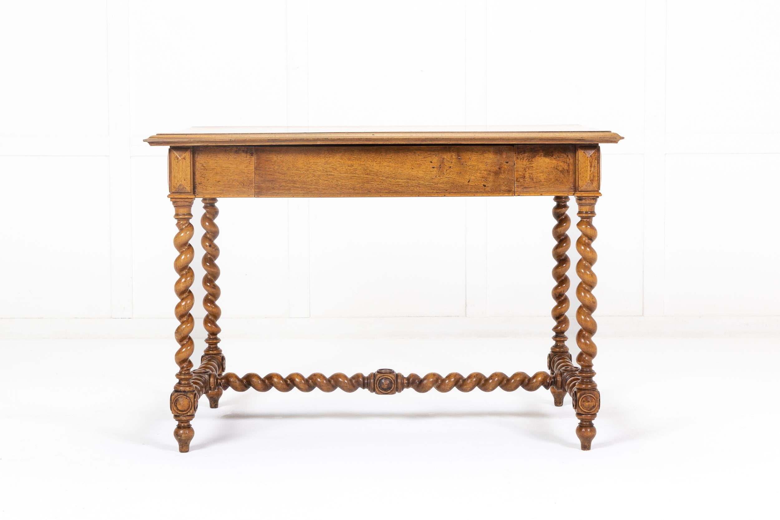 19th century French walnut side table having a rectangular moulded plank top. The frieze has a single, concealed central drawer. Supported by elegant clockwise and counter-clockwise barley twist legs, connected by a turned traditional