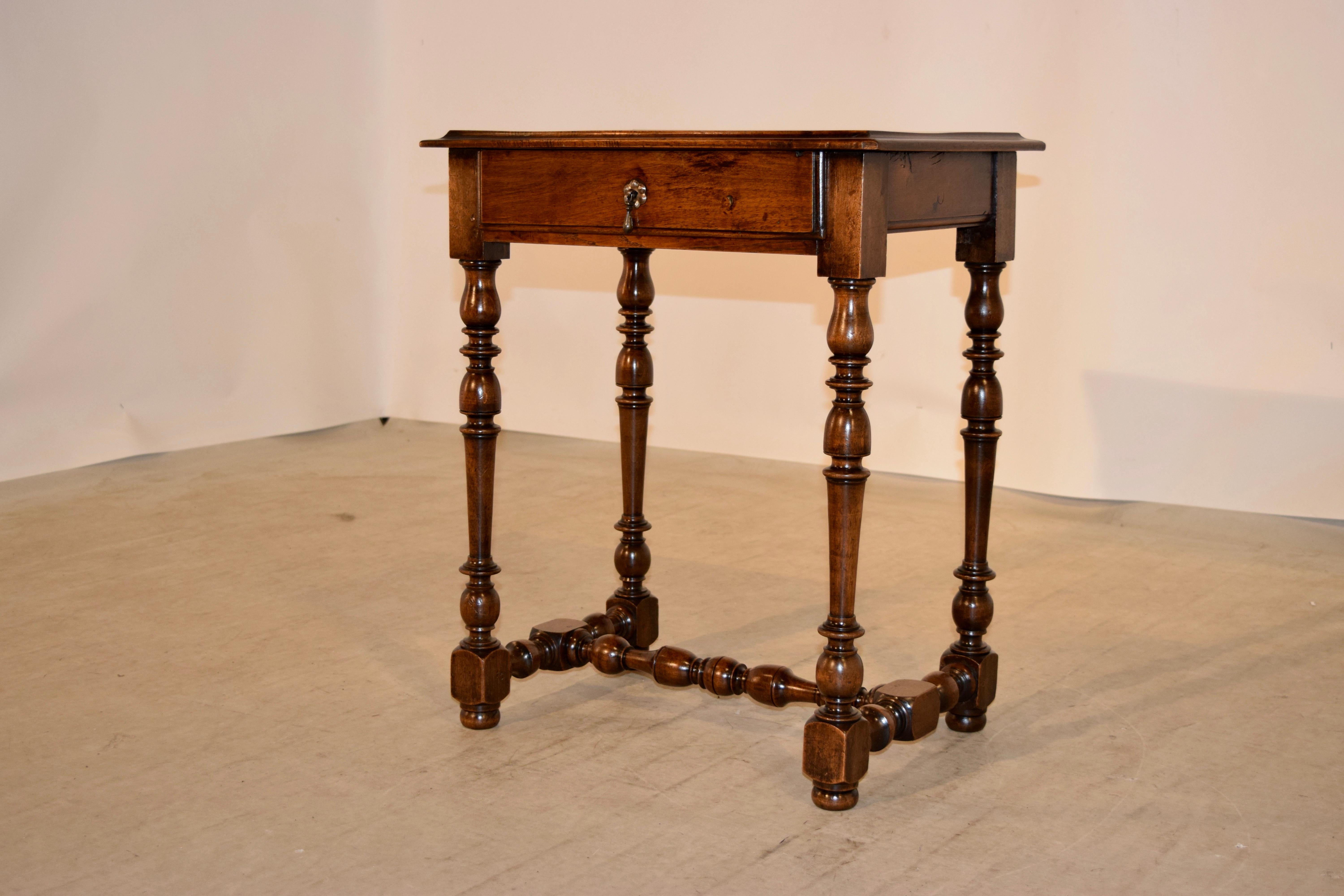 19th century walnut side table from France with an exquisitely figured top with a deeply bevelled edge following down to a simple apron and a single drawer. It is supported on hand turned legs joined by matching stretchers and raised on hand turned