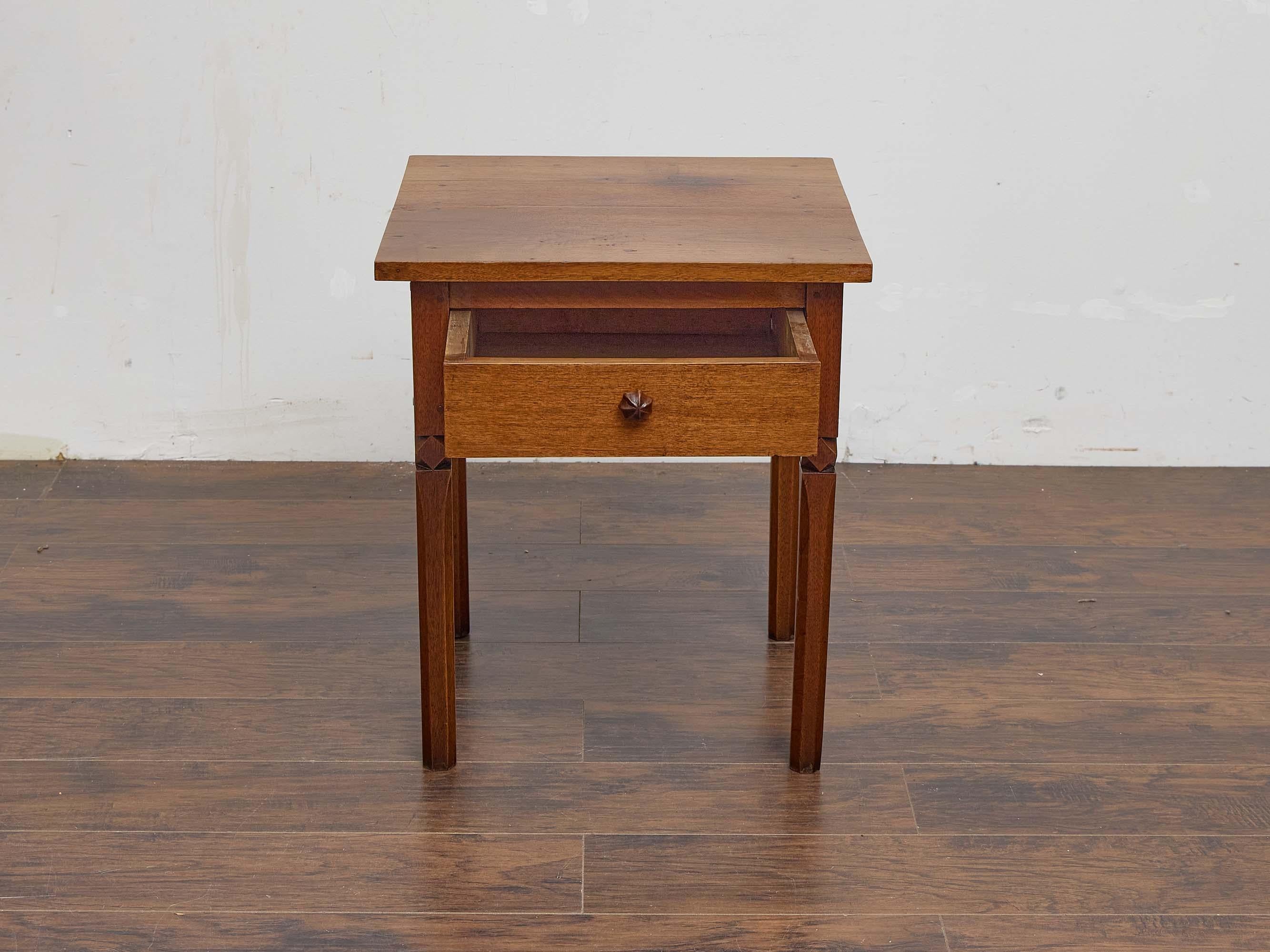 Table d'appoint en noyer français du XIXe siècle, combinant des lignes simples et des détails sculptés raffinés. Le plateau carré repose sur un seul tiroir, équipé de sa tirette d'origine en bois sculpté. La façade du tiroir est sobre, ce qui permet