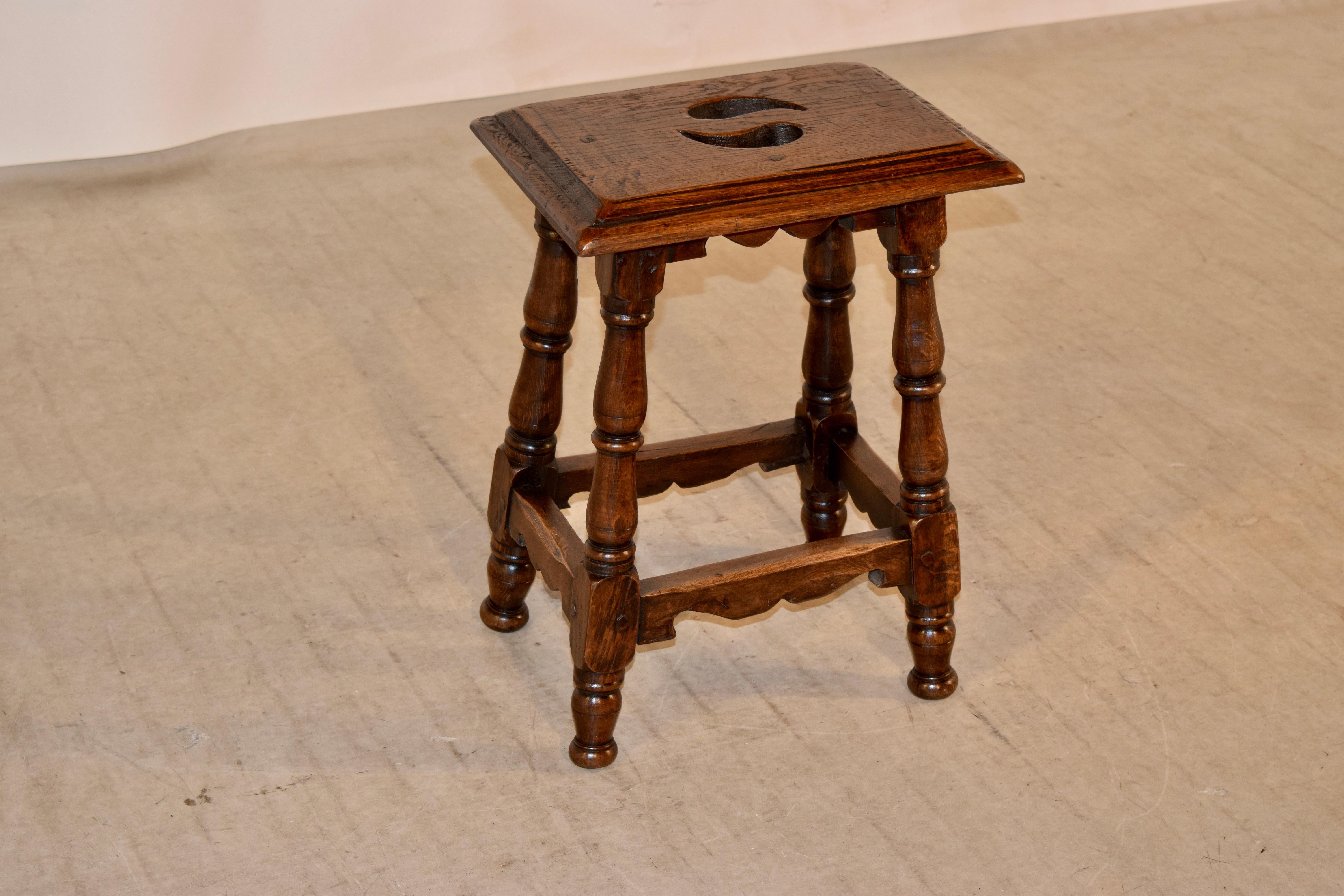 19th century walnut stool from France with a wonderfully thick top which has a handle design cutout of the top and a multi-level beveled edge, following down to a lovely hand scalloped apron and hand-turned splayed legs joined by hand scalloped