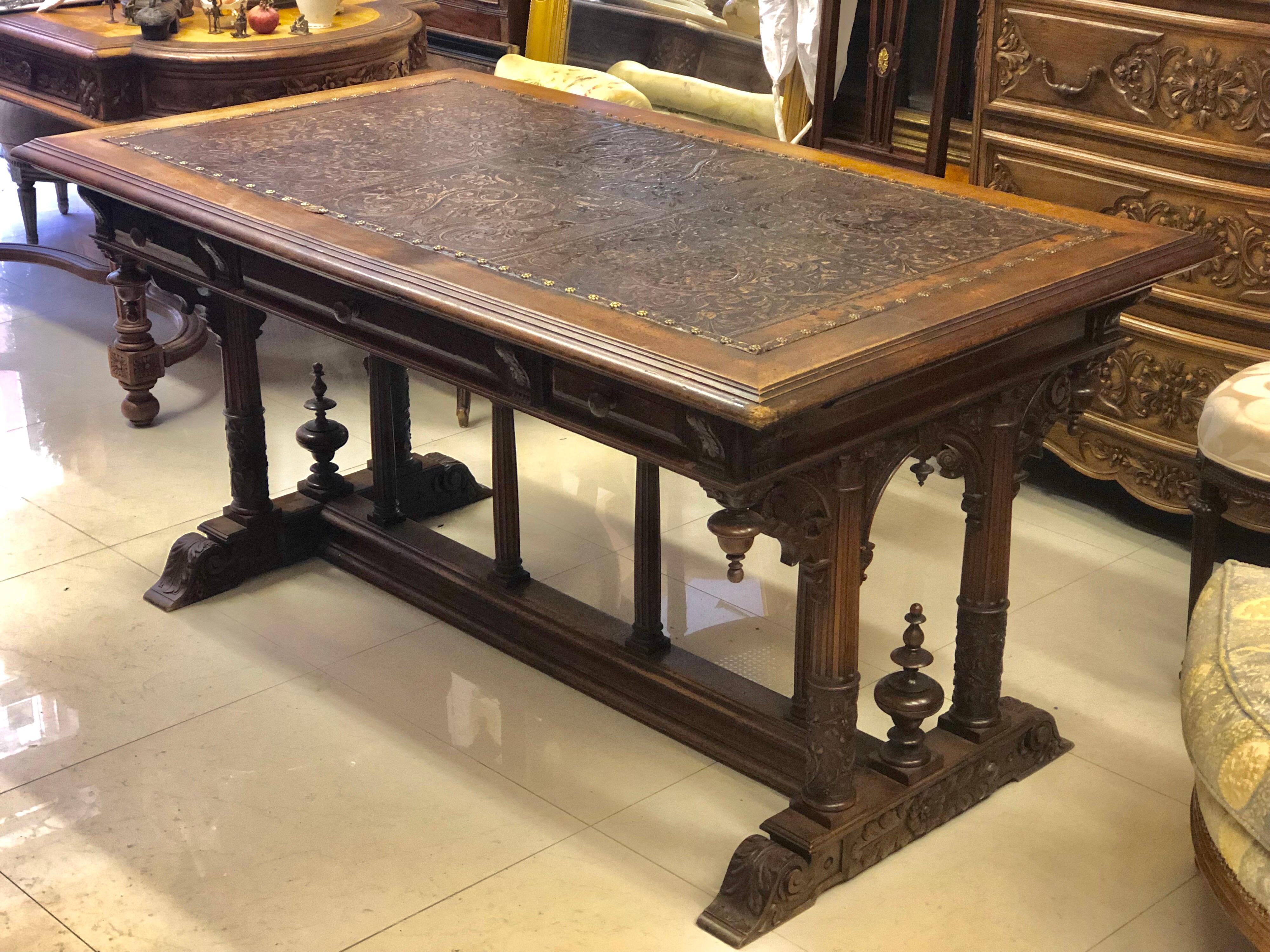 19th century French walnut three-drawer desk table with moulded and carved acanthus leaves, scrolls and foliage decorated with arcane. The base is standing on four columns on a skid and spacer in H with four balusters. The leather top is in great