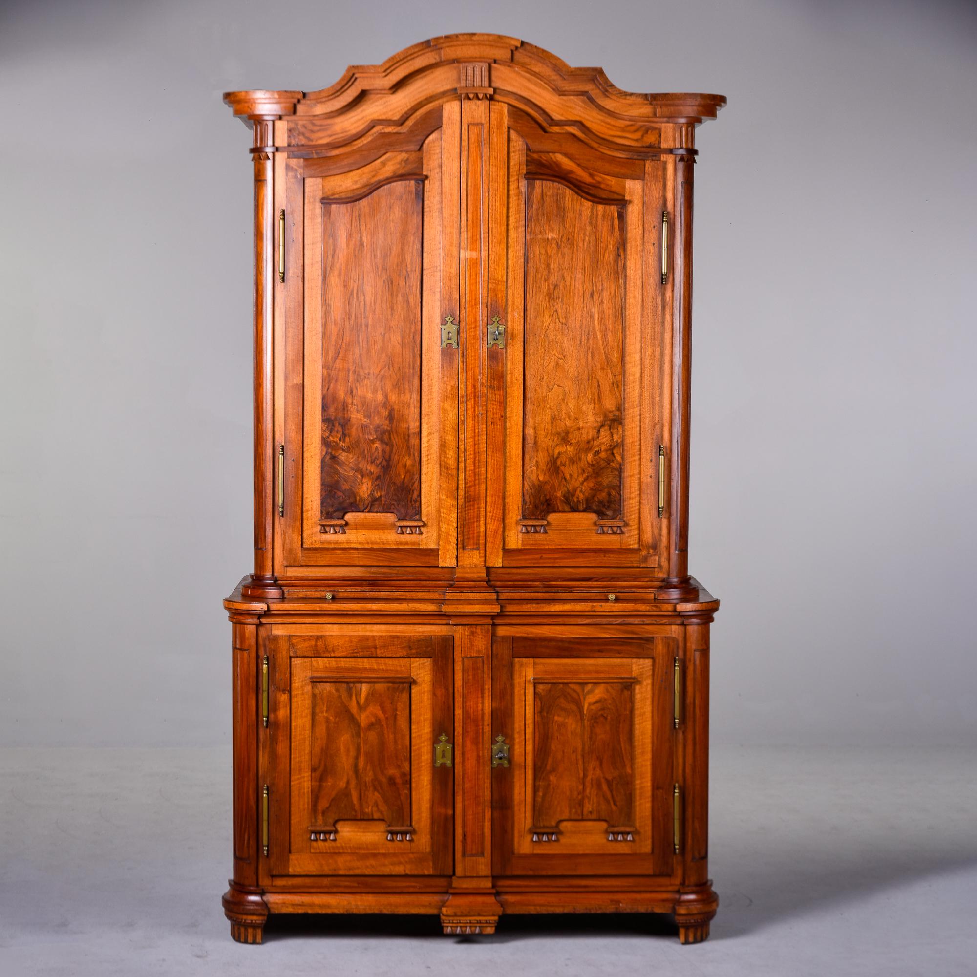 Found in France, this two piece walnut cupboard dates from the 1880s. Walnut has a rich, warm patina and is accented with burlwood panels on door insets. Top piece has an arched pediment and two hinged doors with functional lock that open to storage