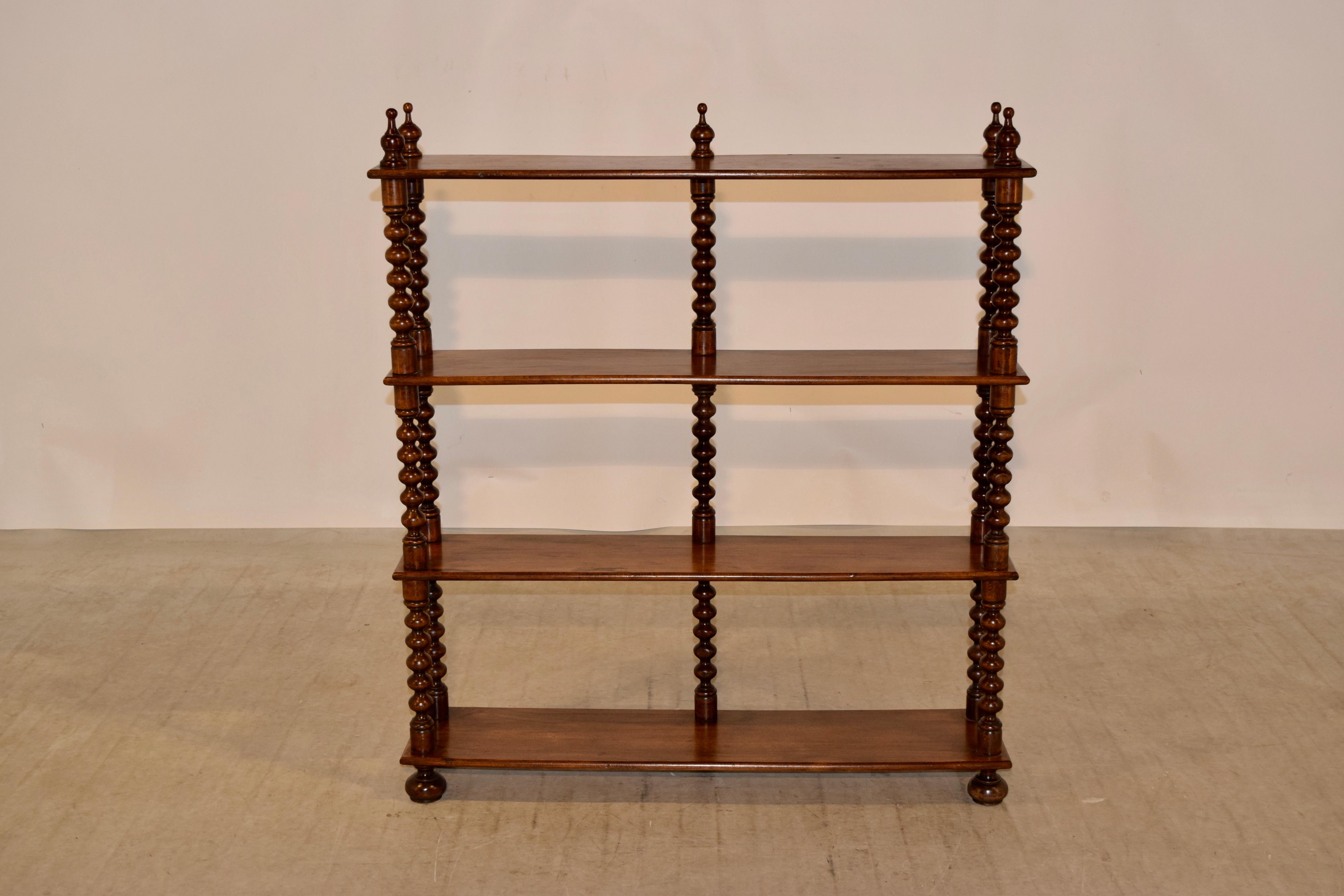 19th century walnut wall shelf from France with four shelves, decorated on the top with hand-turned finials and the shelves are separated by hand-turned bob shelf supports. Raised on hand-turned feet. Slight staining to shelves from age and use.