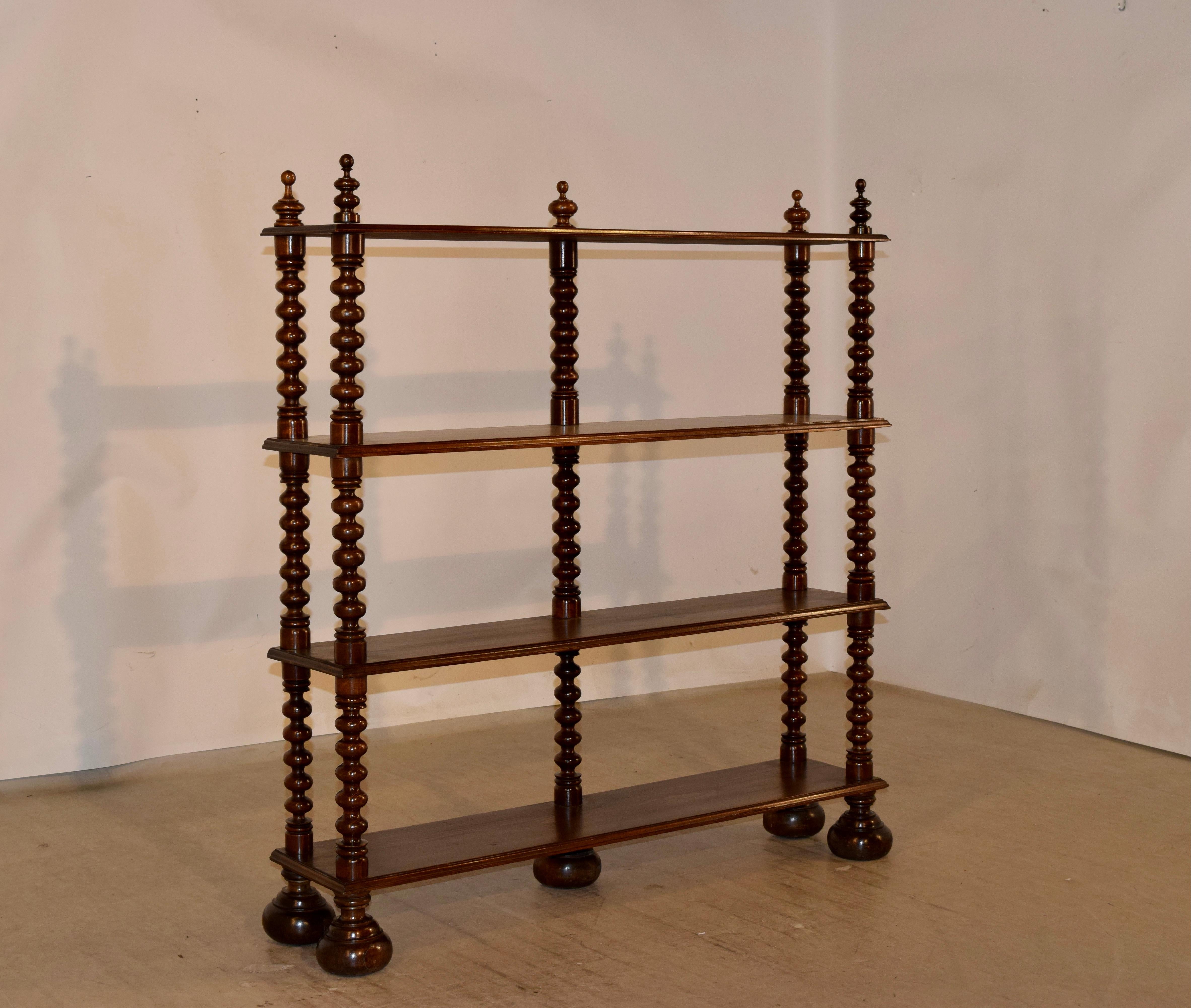 19th century walnut wall shelf from France with four shelves, decorated on the top with hand-turned finials and the shelves are separated by hand-turned bob shelf supports. Raised on hand-turned feet. Shelf height measures 12 inches and the shelf