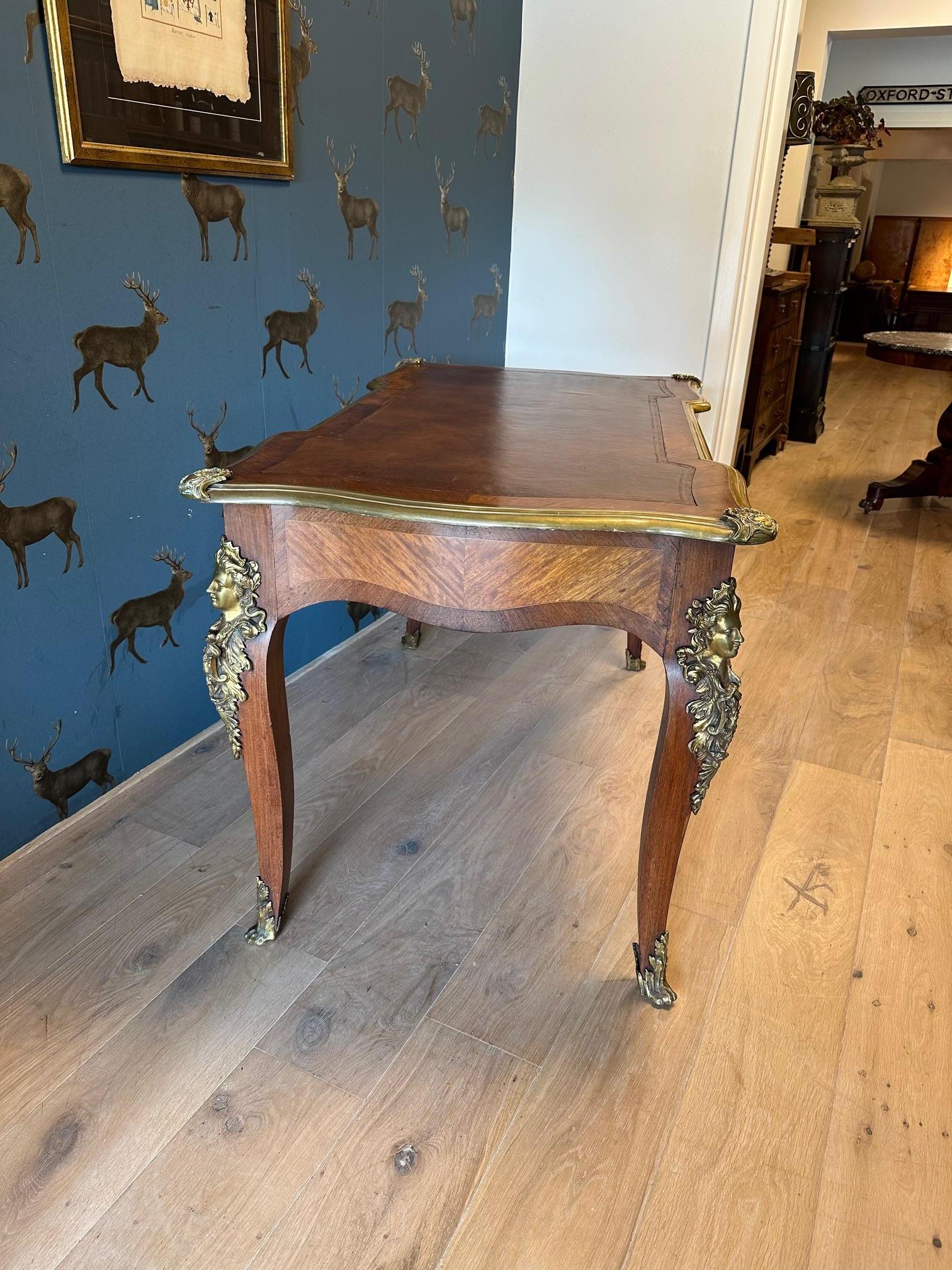 Beautiful antique walnut writing table with brown leather top. The table has 3 drawers on one side and the other sides are not drawers but look like they are. The table is richly decorated with ormolu-bronze ornaments. The whole has a beautiful,