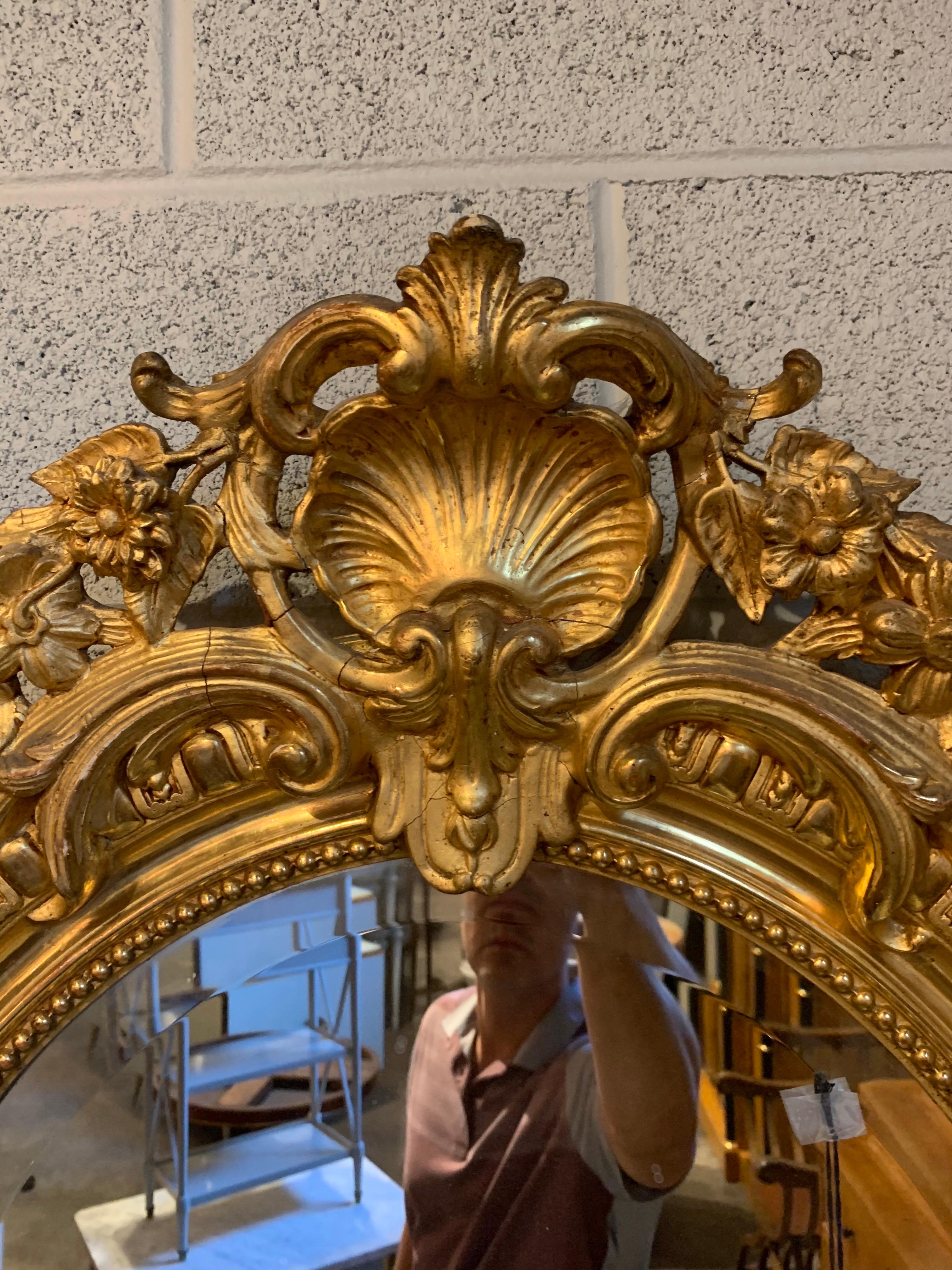 Magnifique miroir français du 19ème siècle, de forme ovale, doré à l'eau. De jolies images florales ainsi que des coquillages sur le dessus du miroir. Une pièce très élégante pour une maison raffinée !