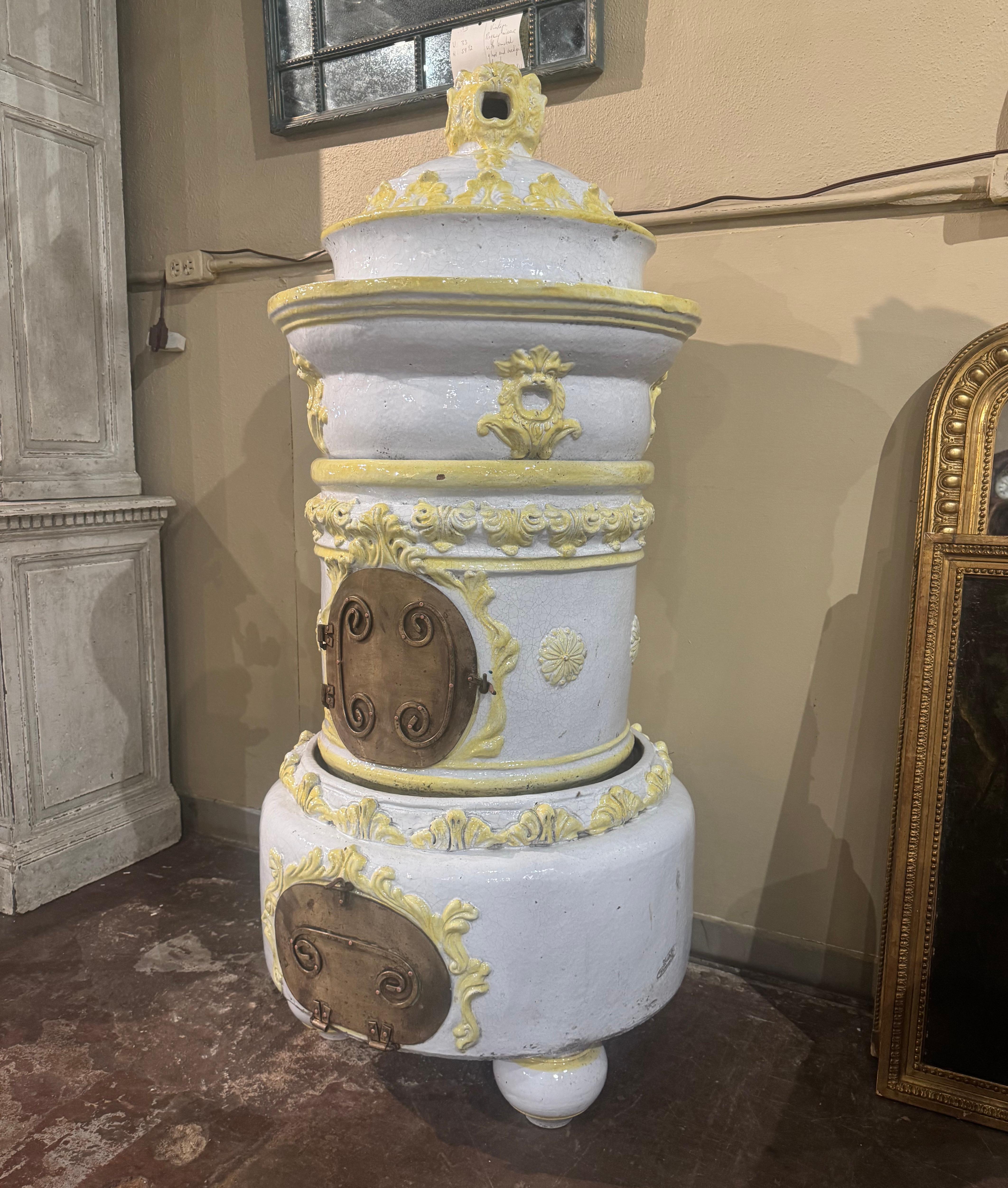 This tall, antique stove was created in Lyon, France, circa 1870. Sited on bun feet and built in four separate sections, this colorful ceramic piece has a small brass door at the bottom to collect ashes, and a center door to feed coal or wood into