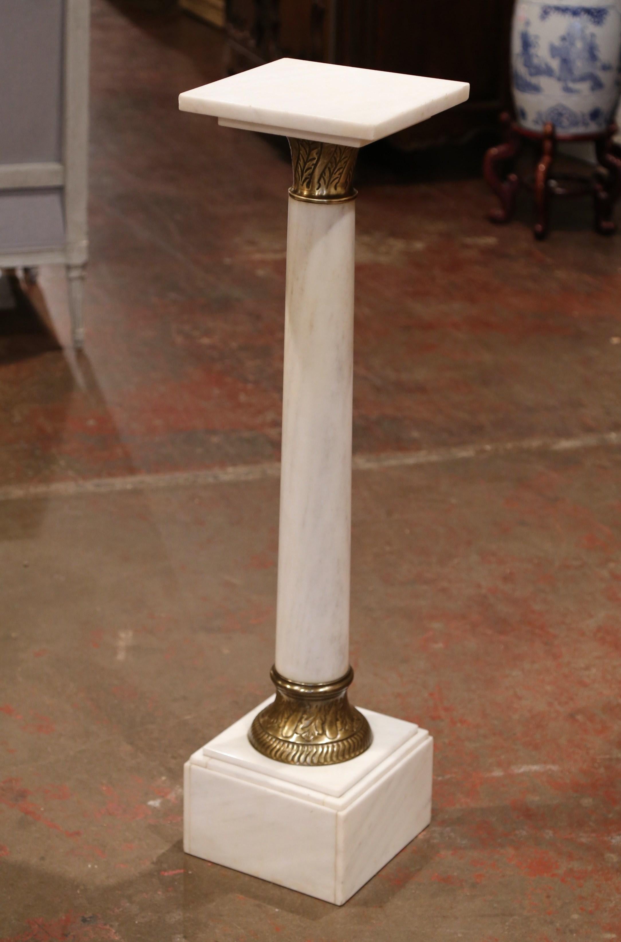 This elegant, antique white marble pedestal table was crafted in France, circa 1870. The Napoleon III pedestal sits on a sturdy square plinth base embellished with a repousse leaf motif brass mount at the bottom. The tall, round stem is decorated at