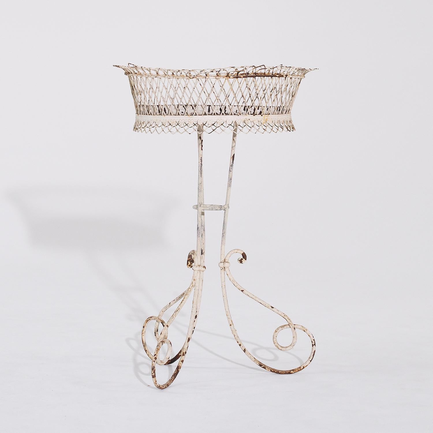 An antique French white jardiniere in the style of Arras, in good condition. This circular French Provincial plant stand is finely worked in iron with scrolling wire-work lattice. Antique white painted crackled patina. The plant stand has its