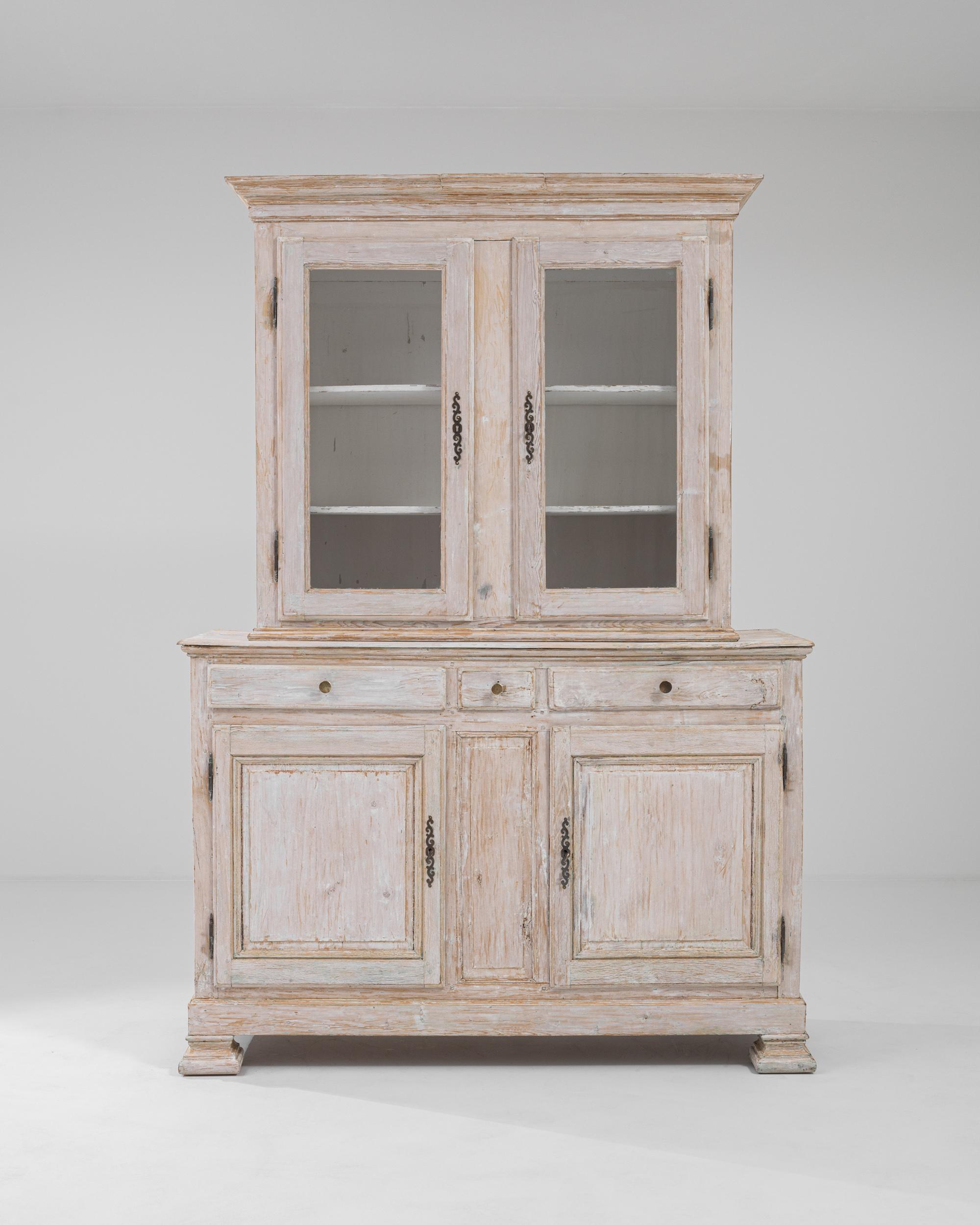 A timeworn patina gives this antique vitrine an air of romance. Built in France in the 1800s, the silhouette has a Provincial simplicity, graceful yet unadorned. The windows of the cabinet give a view onto a set of shelves, which would likely