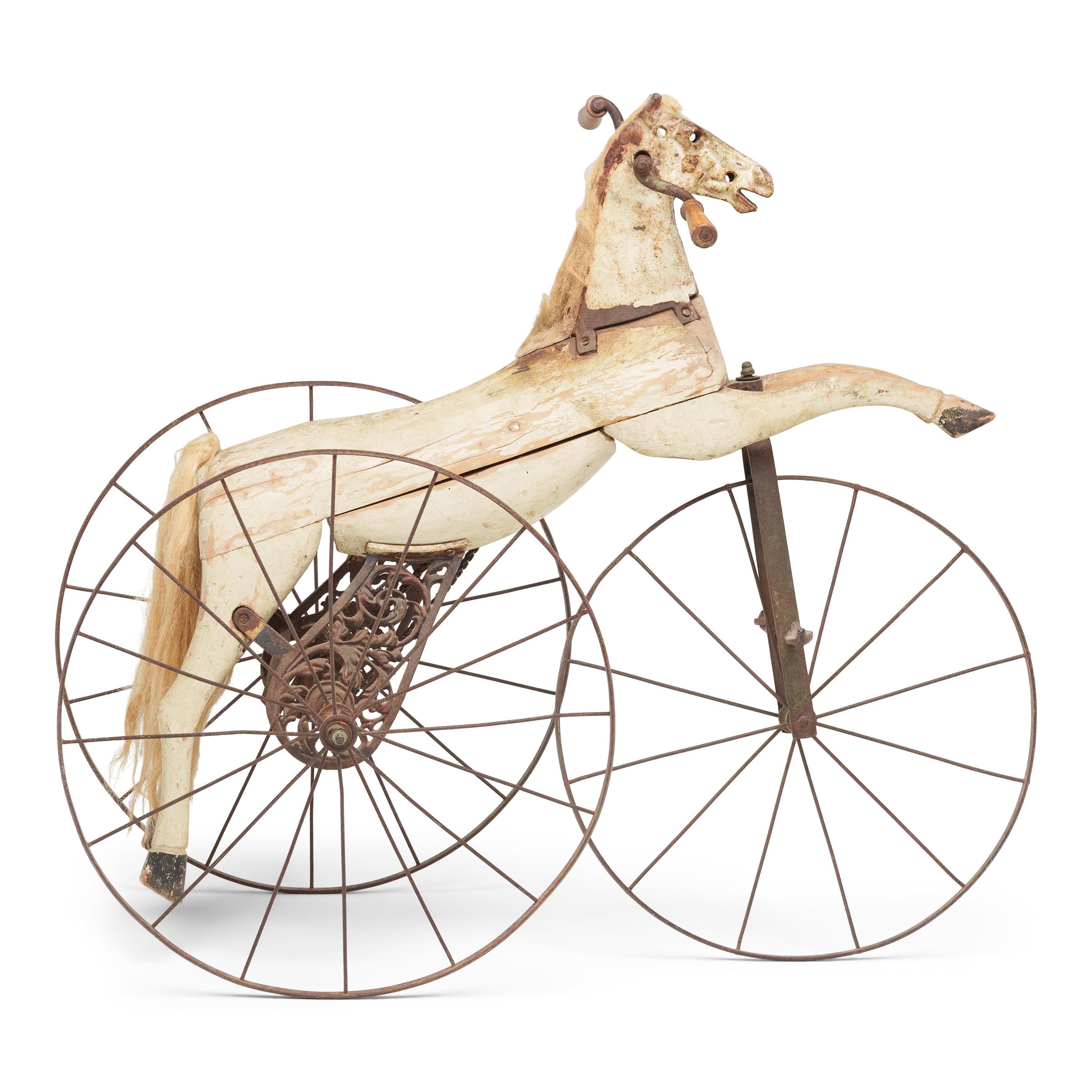 A 19th century French velocipede of a white pony, the horse of polychromed wood with horsehair mane and set upon an iron tricycle.

Deaccessioned from the MacLean Collection of Asian Art.