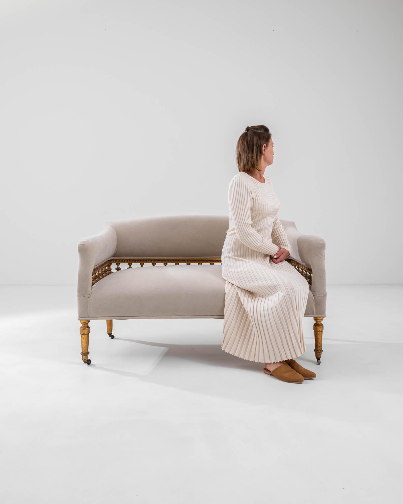 Indulge in the refined comfort of this 19th Century French White Upholstered Sofa. Characterized by beautifully turned spindles and gracefully flared armrests, this sofa is a true testament to the elegance of 19th-century design. The pristine white