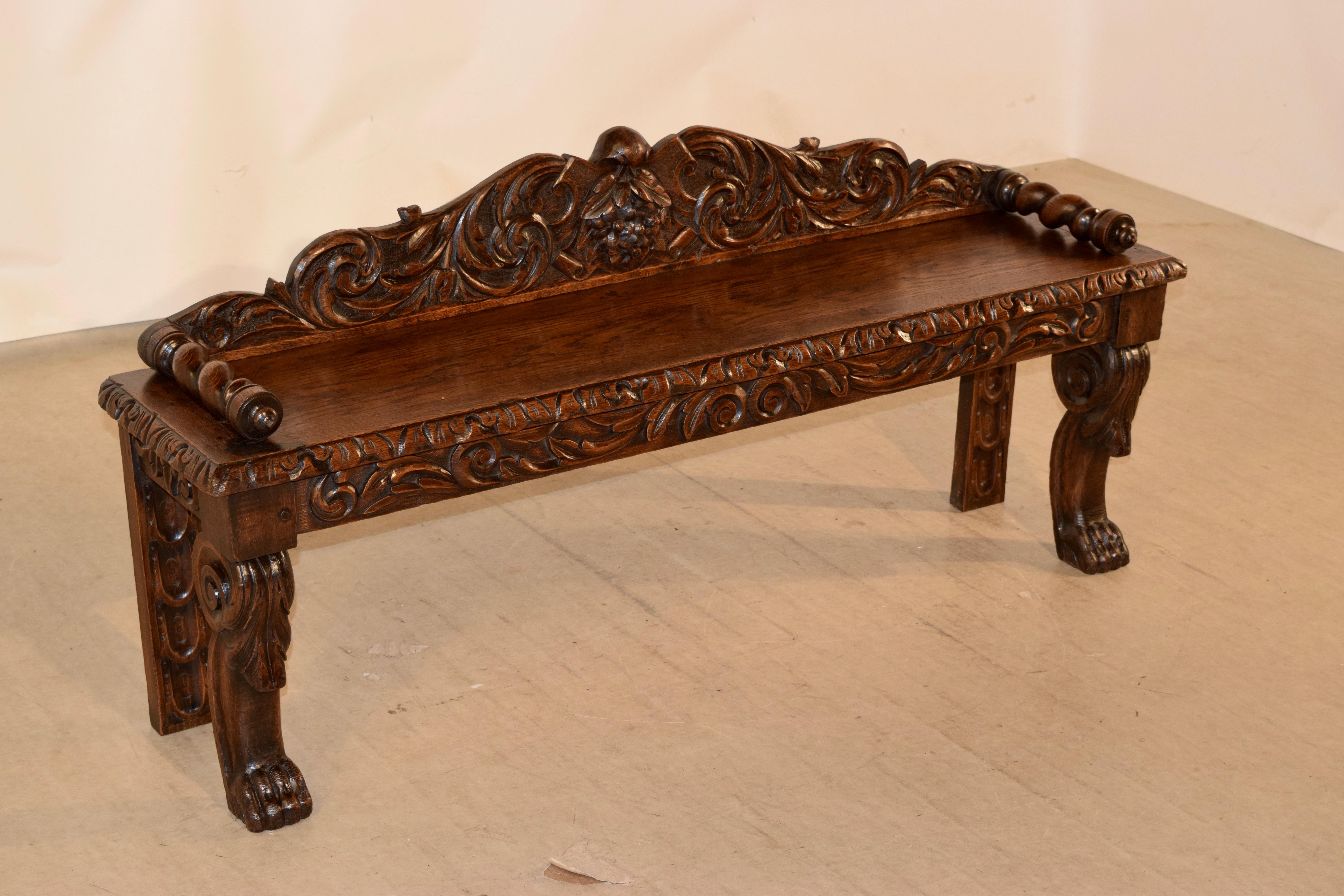 19th century oak window seat from France. The back is scalloped and hand carved decorated with lovely decorations of leaves and grapes, following down to hand-turned barley twist arms over the seat with a beveled and decorated edge on the front and