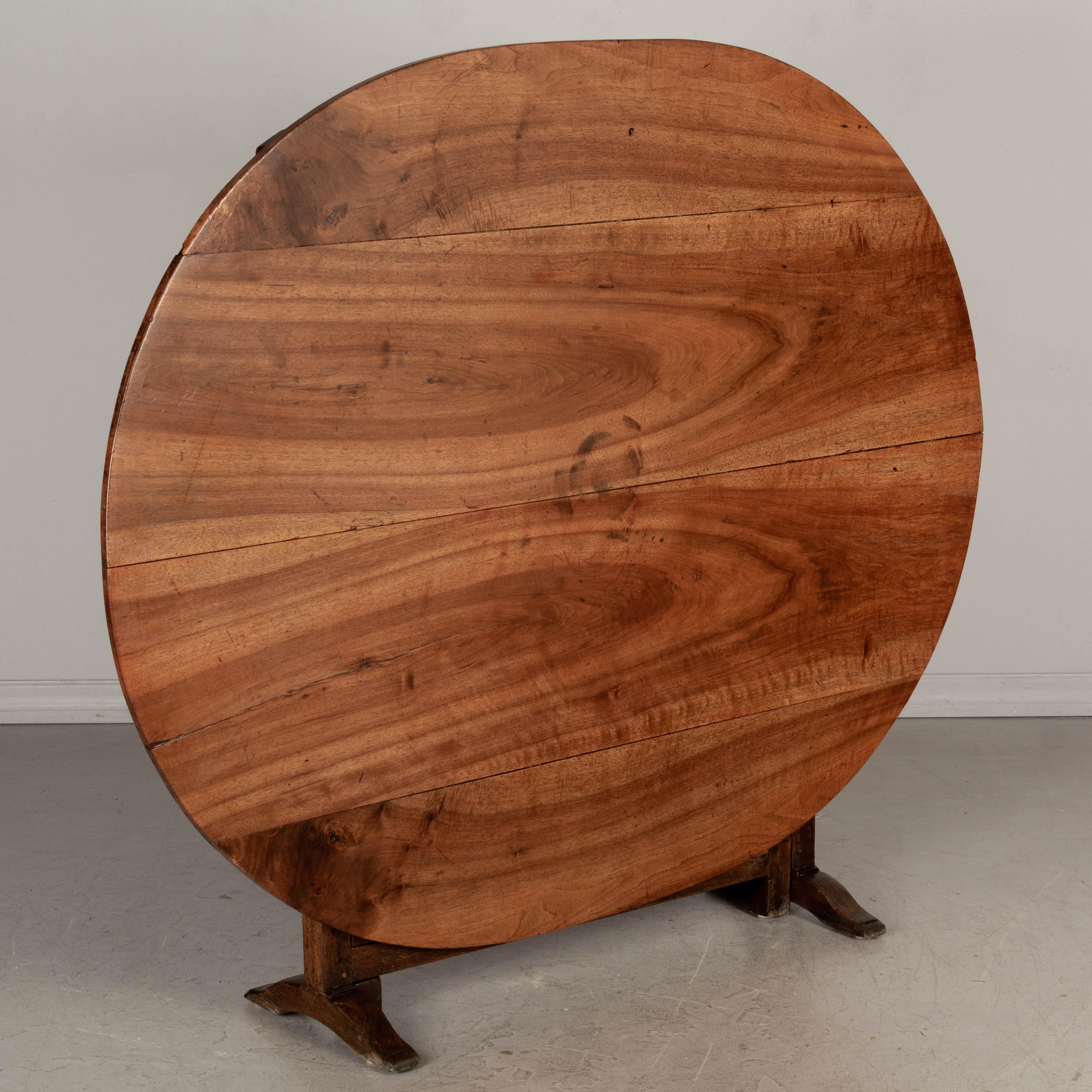 A 19th century French oval wine tasting, or tilt-top table from Burgundy. The top is made from four planks of solid walnut, book-matched. Beautiful grain and character to the wood. The base is made of oak and is thick and sturdy. Well-crafted with