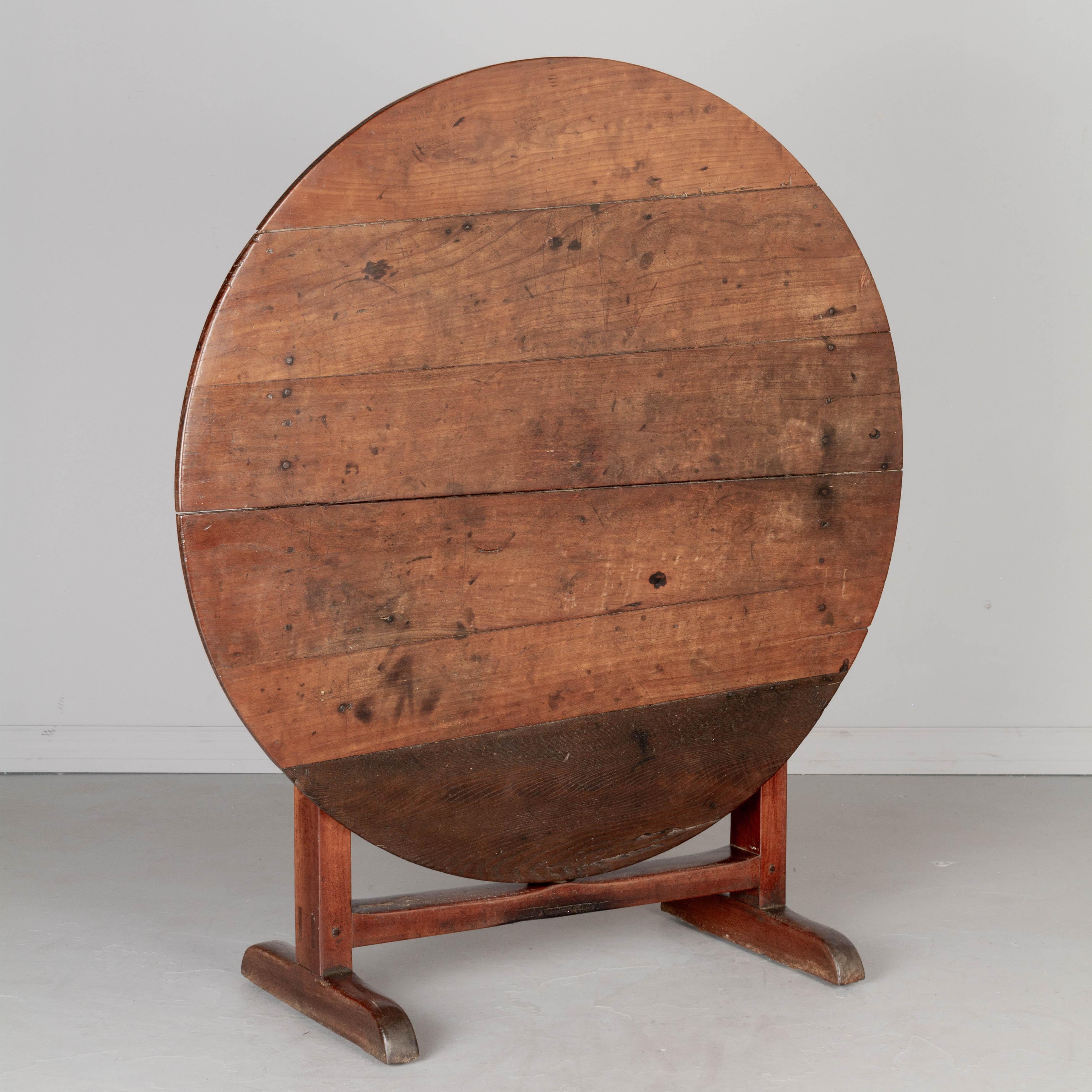 A 19th century French wine tasting, or tilt-top table, made of solid cherry wood. The top has an old restoration with a replaced darker plank of oak. Sturdy and well-crafted with mortise and tenon joints and pegged construction. Nice rustic aged
