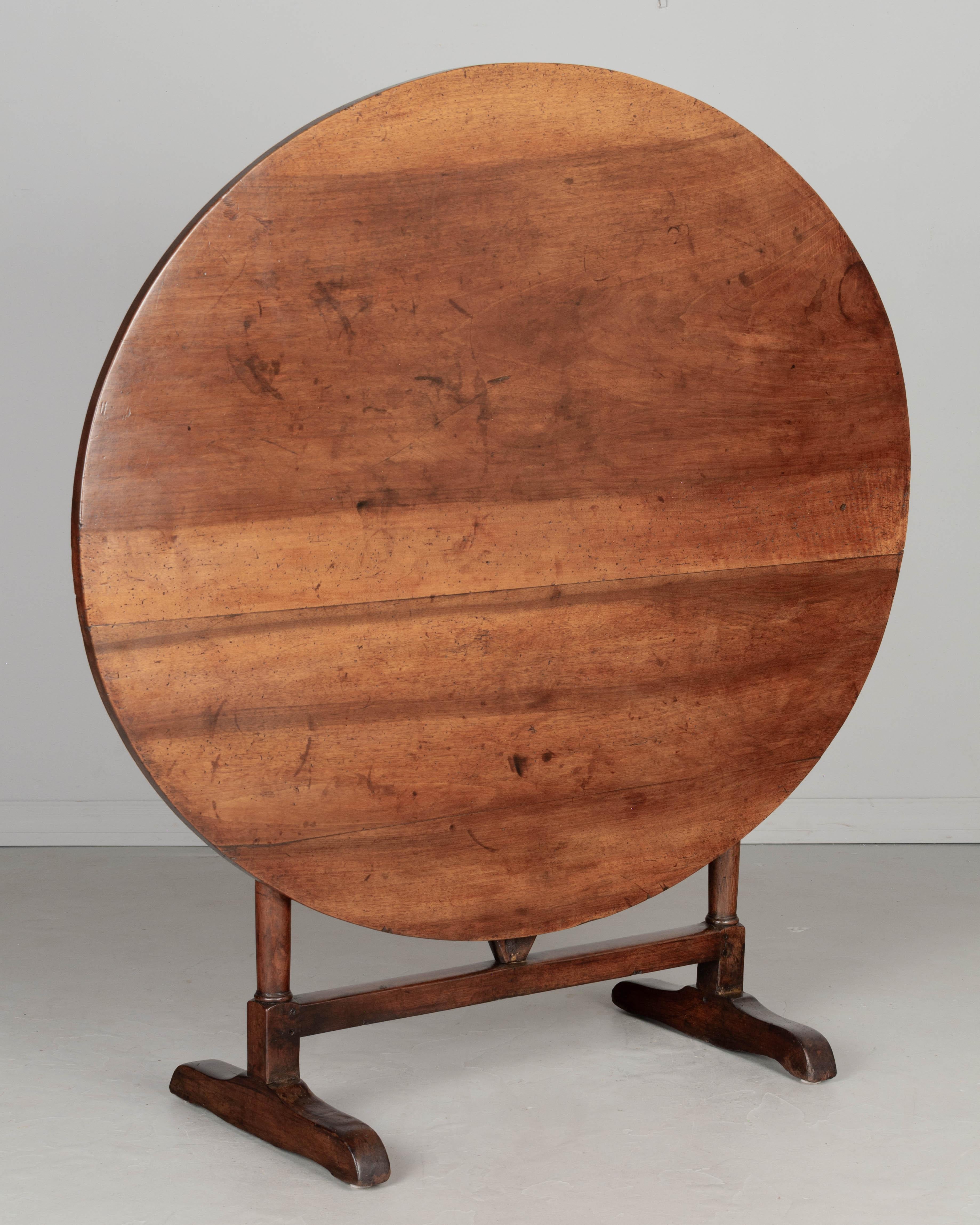 A 19th century French oval wine tasting, or tilt-top table made of walnut. The top is made from three planks of solid walnut, one 24