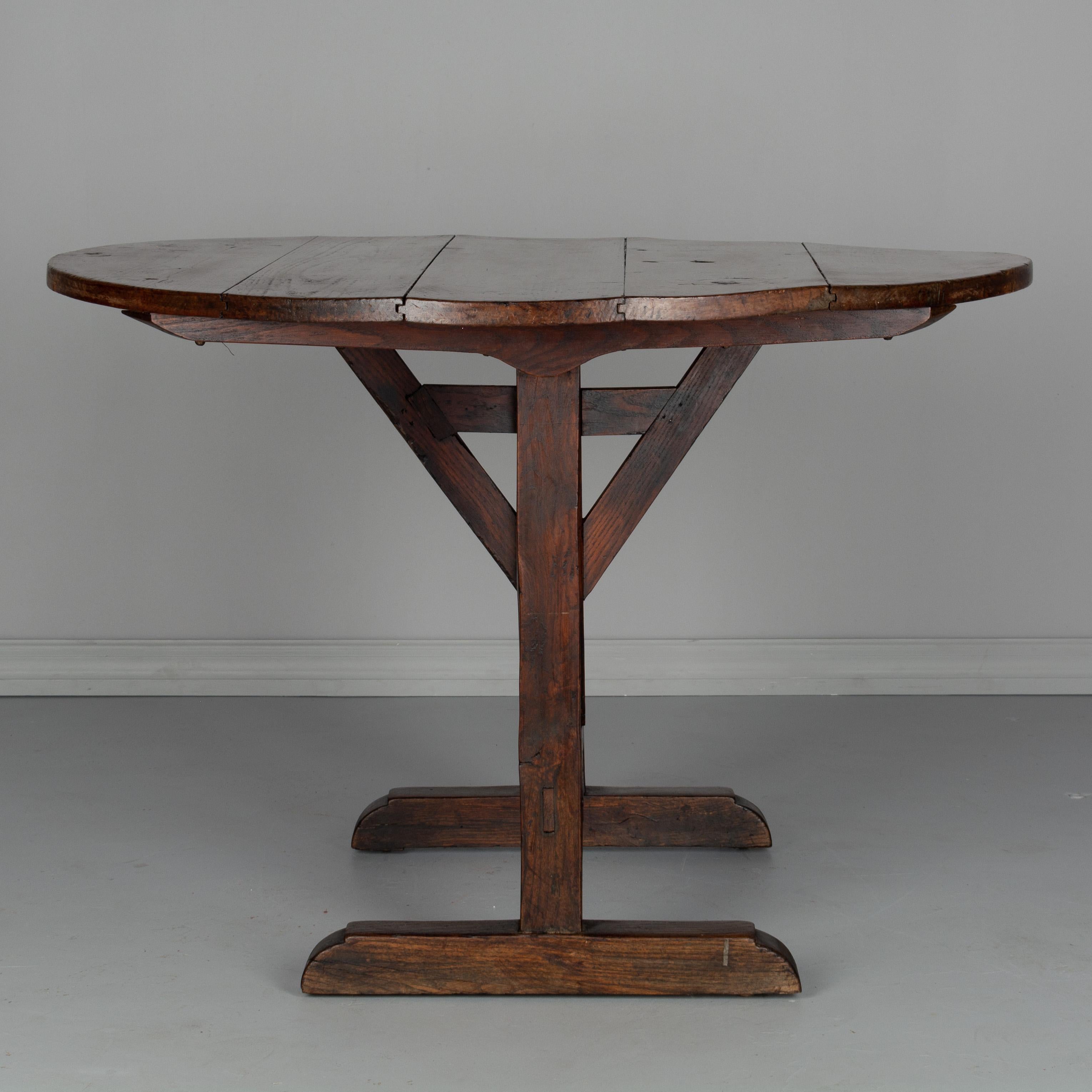 A late 19th century French wine tasting or tilt-top table with a base made of oak and the top made from five planks of poplar. Good and sturdy with mortise and tenon joints and pegged construction. Nice rustic character to the wood with several