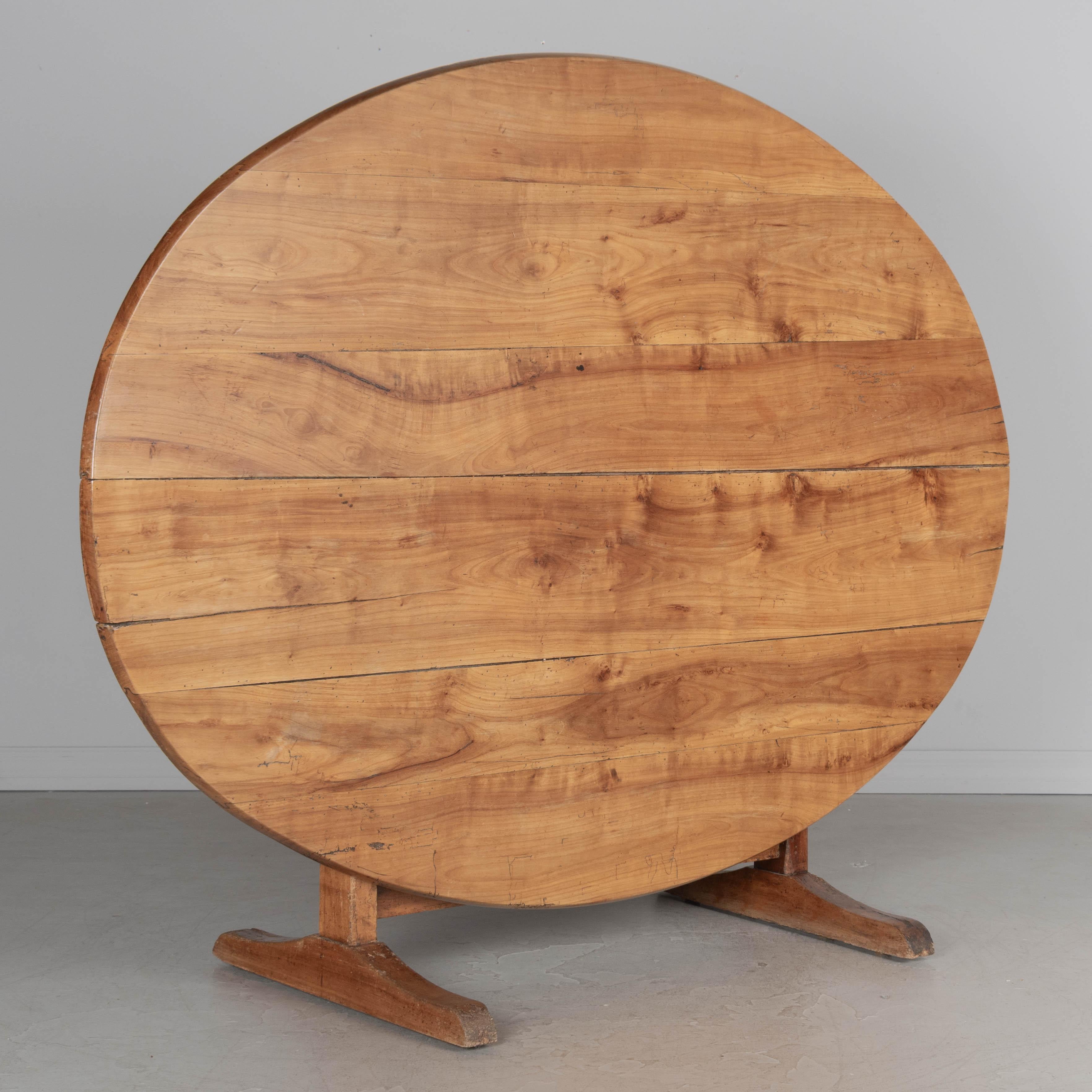 A 19th century French large oval wine tasting, or tilt-top table made of solid cherry. Nice grain and character to the wood. The table is sturdy but the top planks are slightly wavy. Well-crafted with mortise and tenon joints and pegged