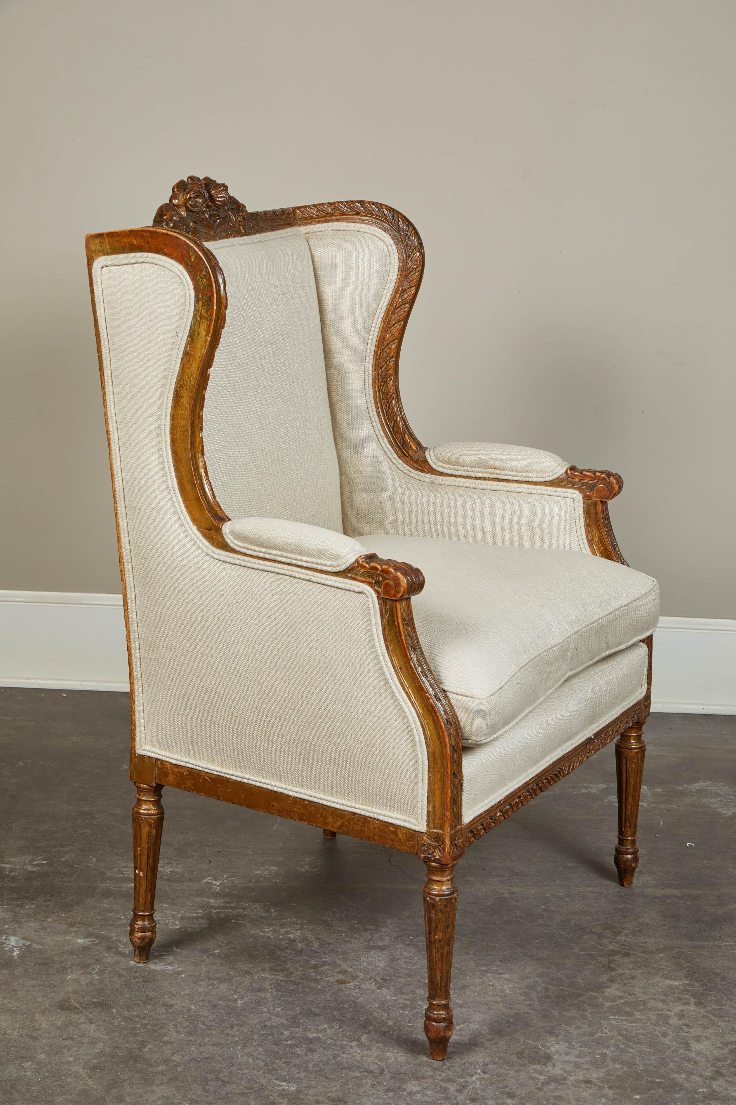 A lovely 19th century French wingback chair. Neutral upholstery, removable cushion and great carved details on a dark-wood frame.