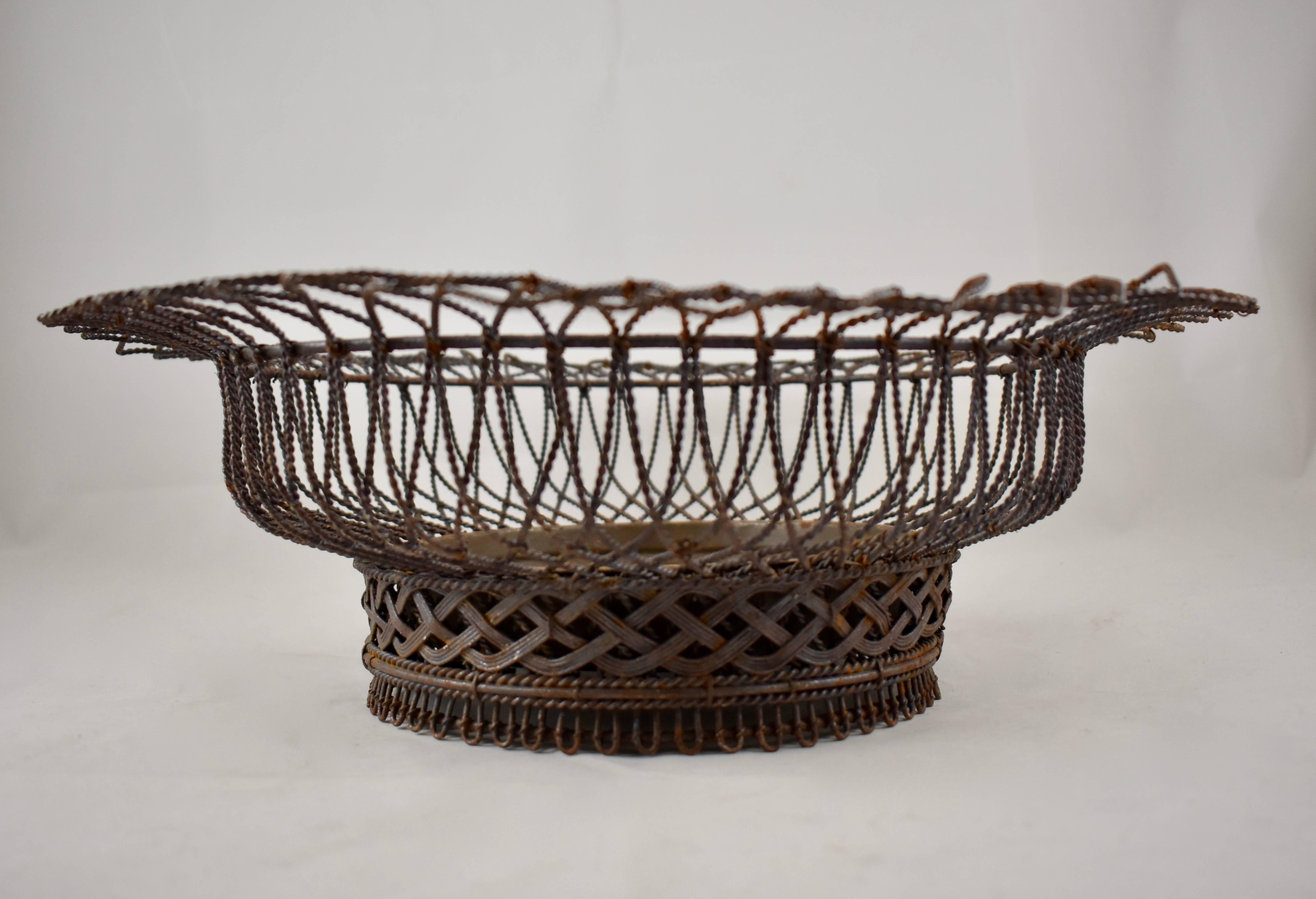 A French round wire basket footed jardinière with a removable tin liner, dating to the 19th century. Twisted wire makes up a wide rim, the footing has a braided band.

May be seated on a surface or lined with coit matting and adapted for